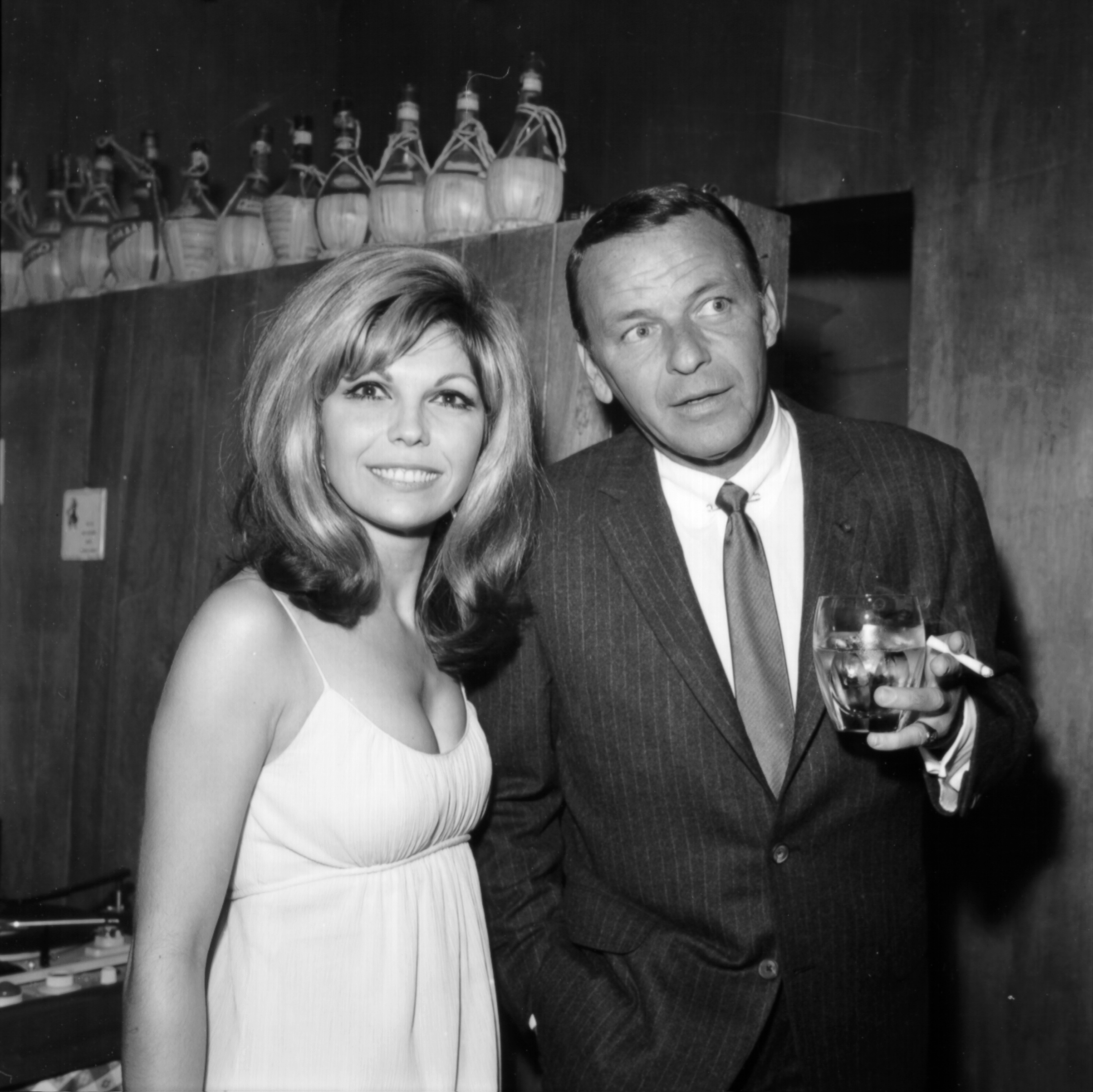 Frank Sinatra's daughter Nancy Sinatra, who's known for "These Boots Are Made for Walkin'," and Frank Sinatra standing together with Frank holding a glass