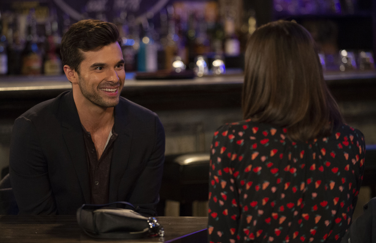 Josh Swickard smiling while talking to a female cast member during a scene on 'General Hospital'