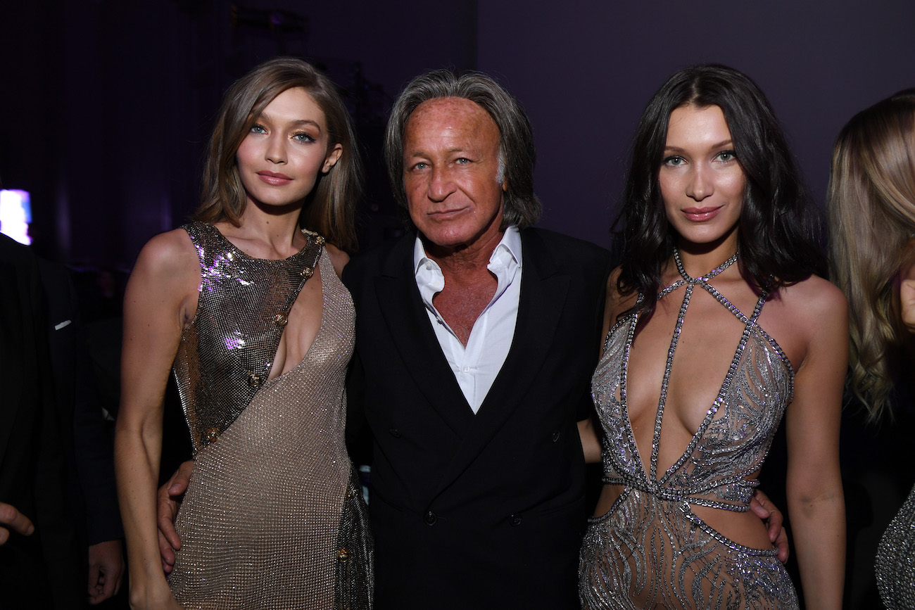 Gigi Hadid and Bella Hadid wearing sparkly dresses with Mohamed Hadid standing in between them