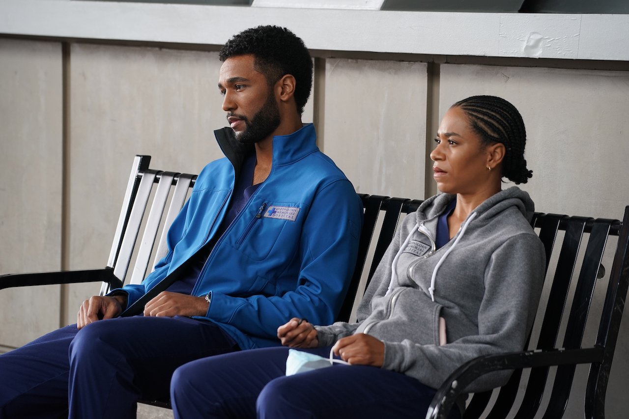 Anthony Hill as Winston Ndugu and Kelly McCreary as Maggie Pierce sit next to each other outside Grey-Sloan on 'Grey's Anatomy'.