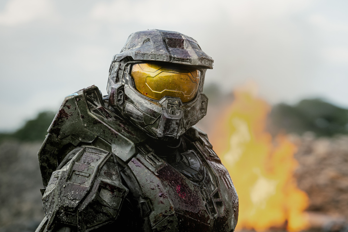 In a scene from the 'Halo' TV show, Master Chief faces the camera in front of a fire
