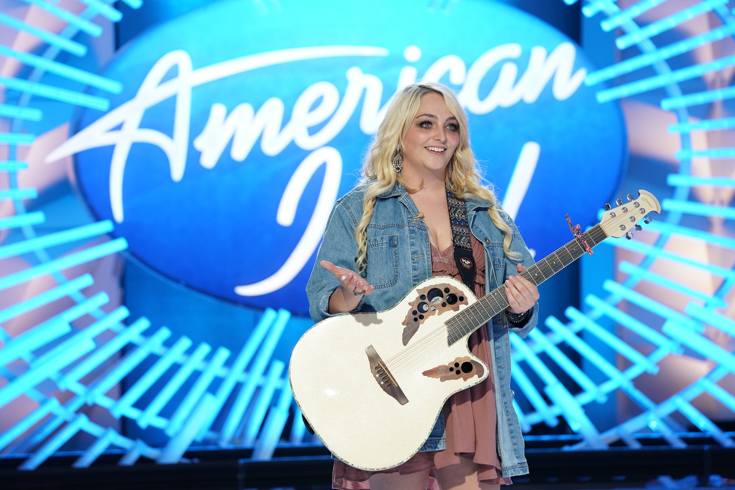 Hunter 'Huntergirl' Wolkonowski standing in front of American Idol sign holding her guitar