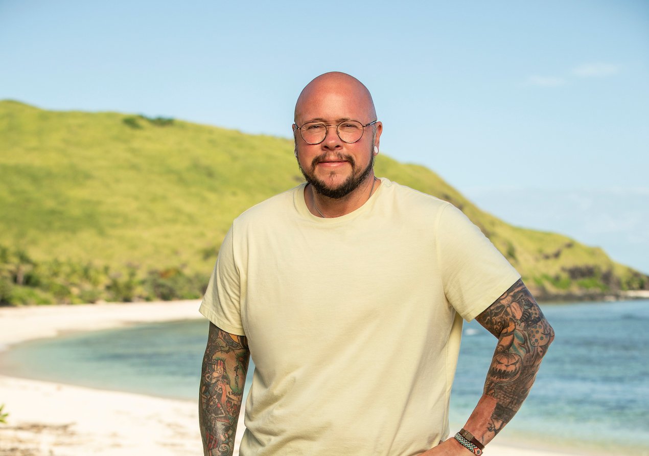 Jackson Fox poses in a t-shirt on the beach for 'Survivor 42'.
