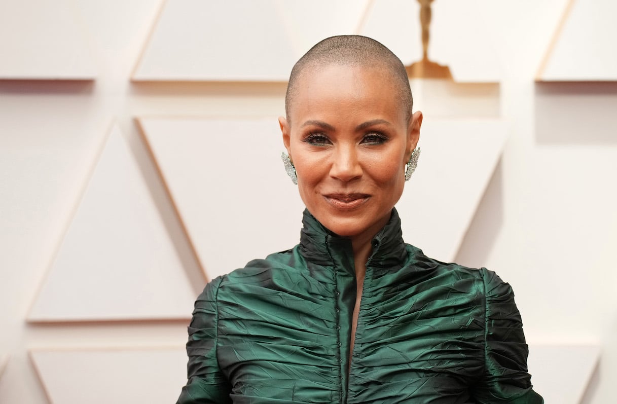 Jada Pinkett Smith on the red carpet at the Oscars with a shaved head and a green dress