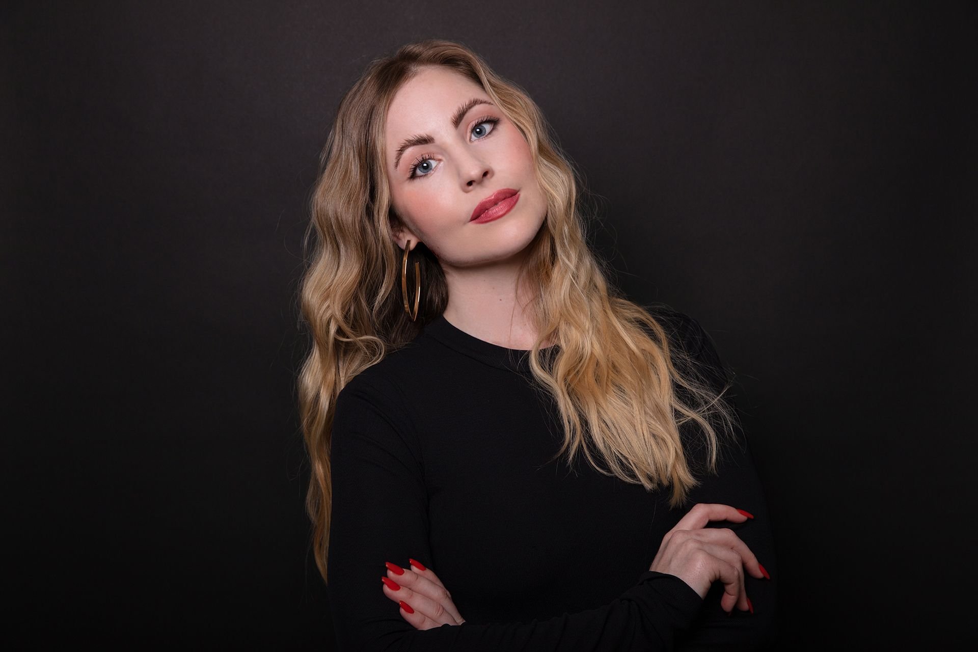 Jamee Ranta crosses her arms while standing in front of a black background