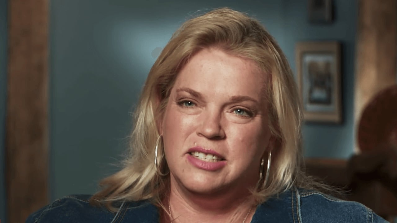 Janelle Brown wearing a green shirt in front of a green background for 'Sister Wives' confessional. 