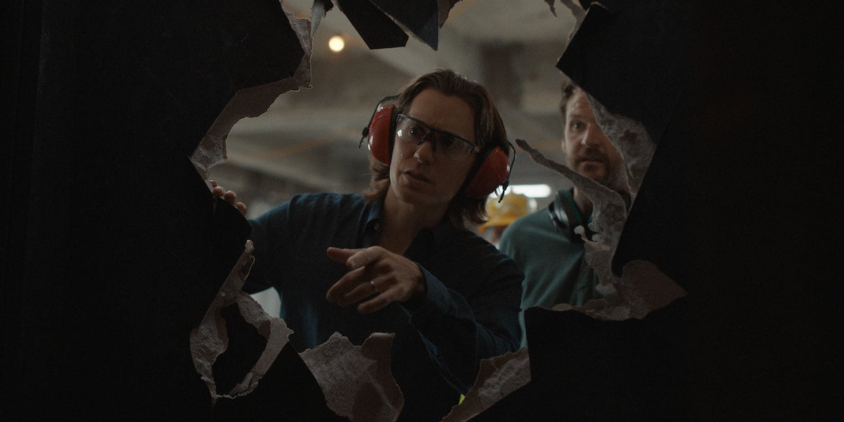 Jared Leto and Kyle Marvin peer through a hole in the wall in 'WeCrashed' Season 1 Episode 2 'Masha Masha Masha'