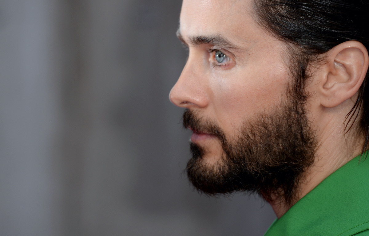 A sideview of Jared Leto’s face as he wears green and poses