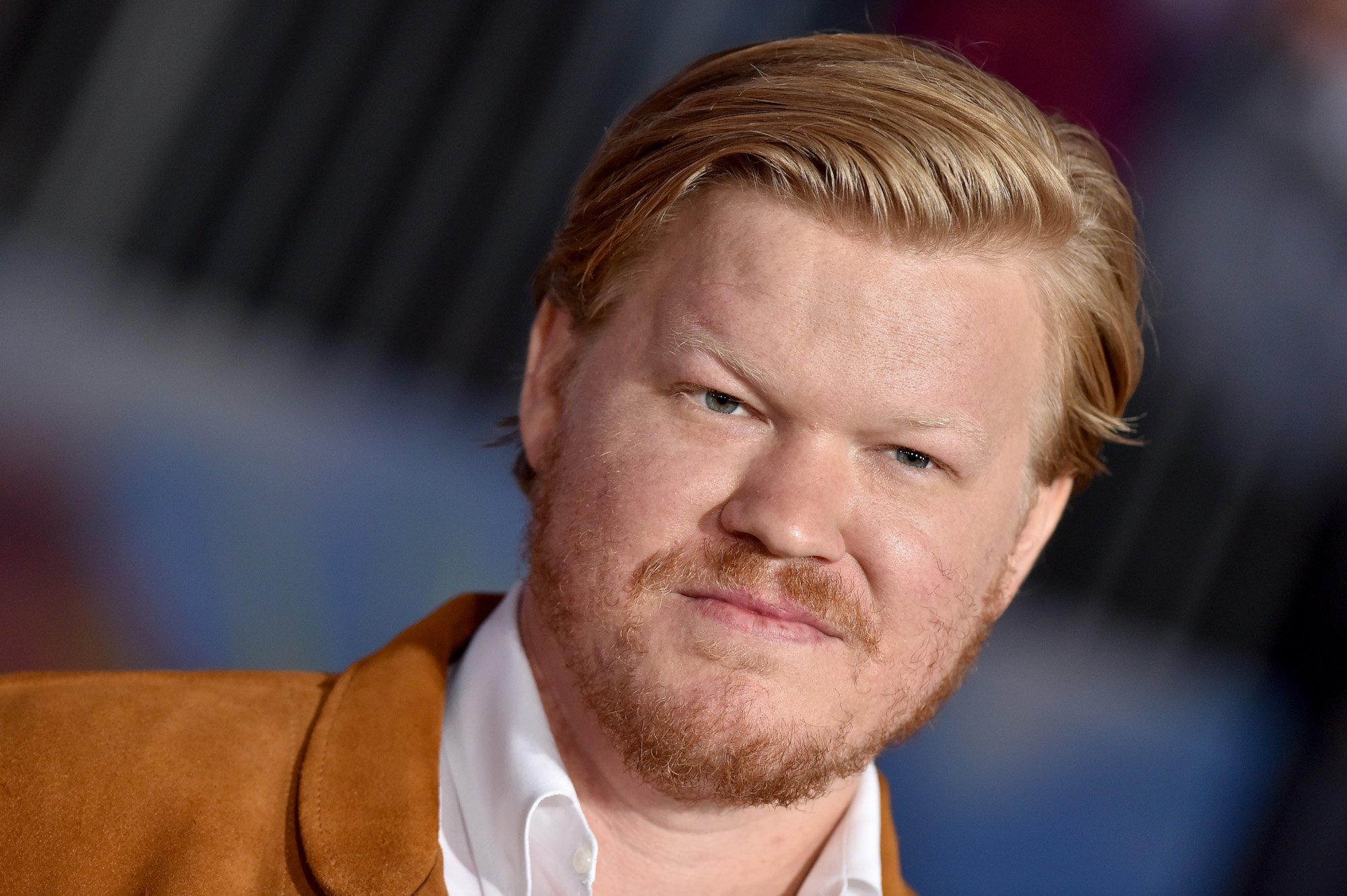 'Breaking Bad' actor Jesse Plemons at the premiere for 'El Camino.' He's wearing a white collared shirt and orange jacket, and his hair is slicked to the side.