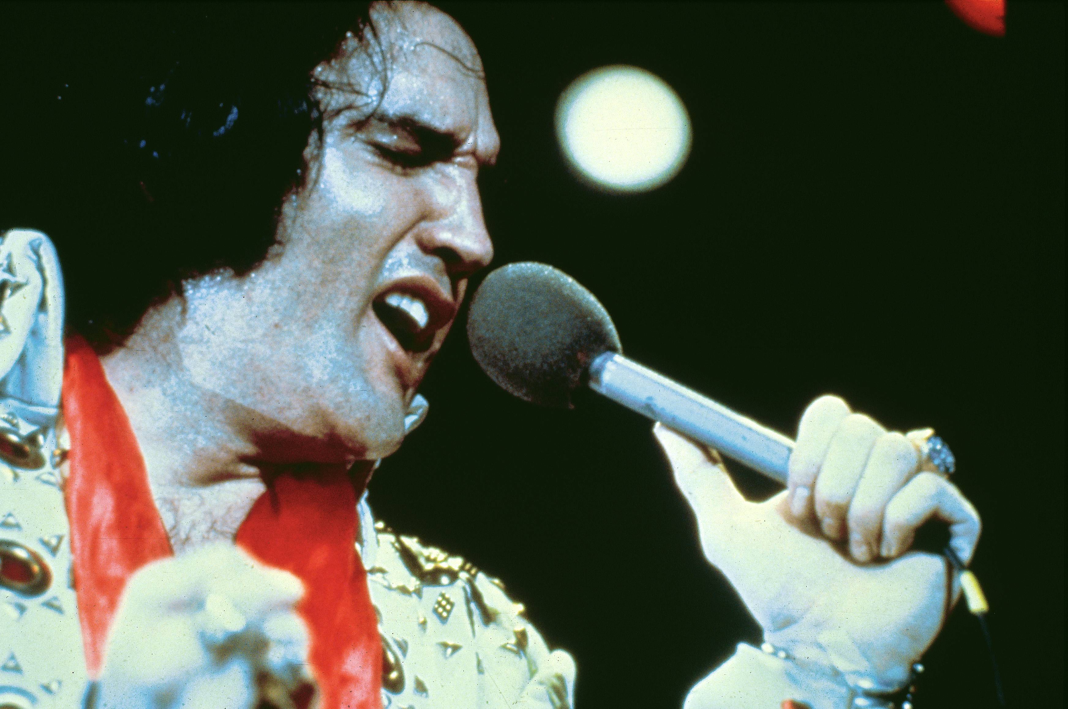 Elvis Presley singing a song into a microphone