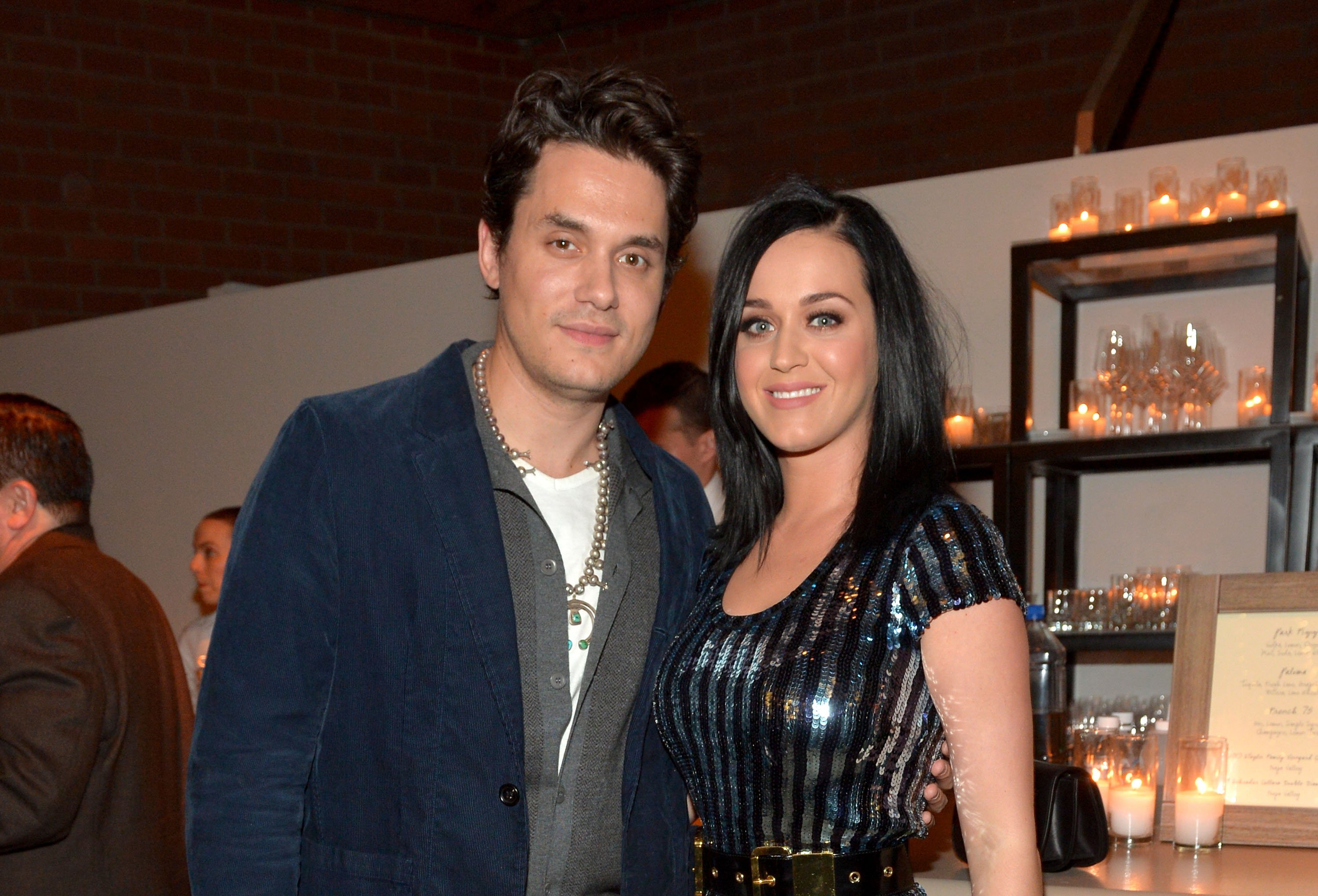 John Mayer and Katy Perry standing near lit candles