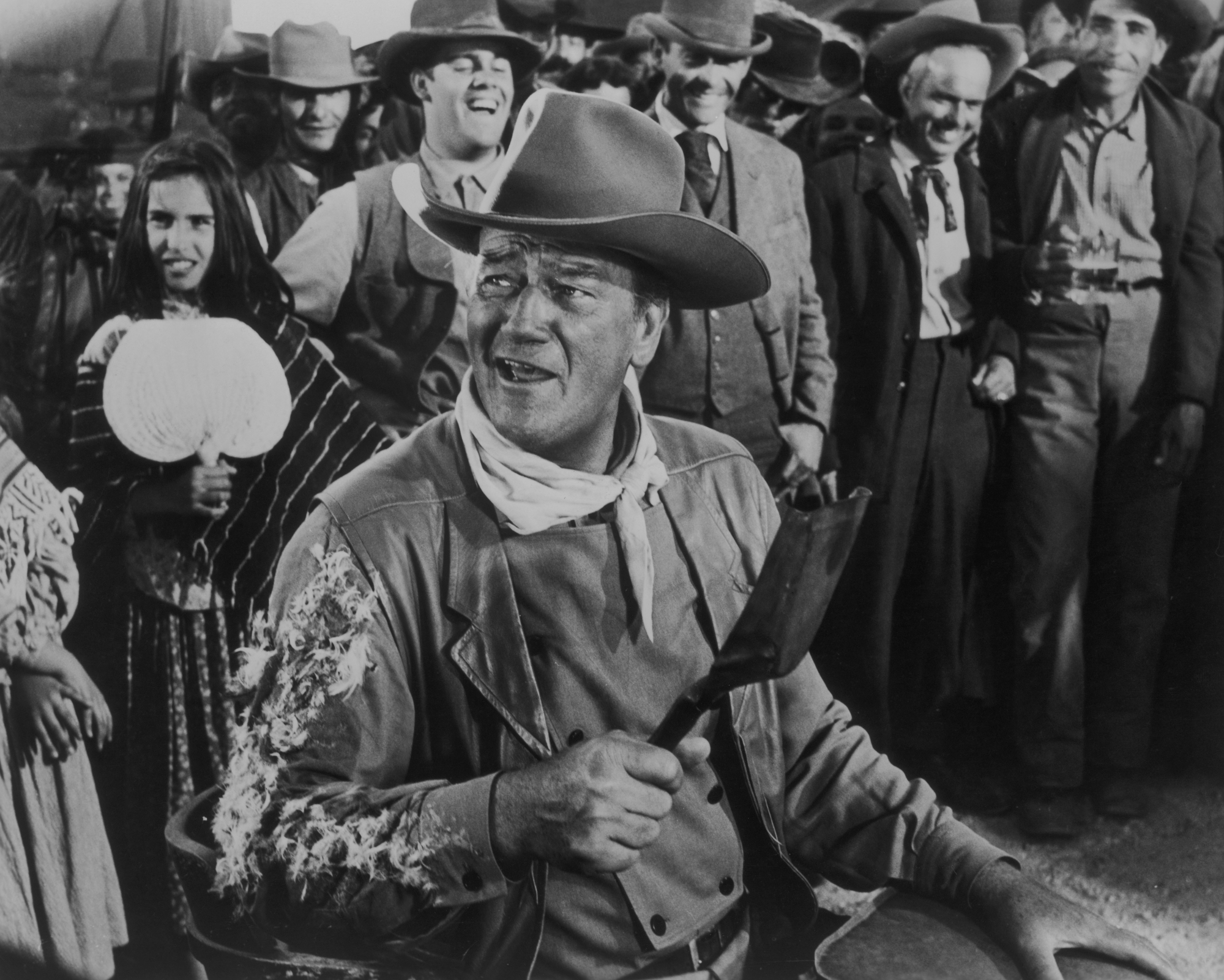 John Wayne as George Washington 'G.W.' McLintock in 'McLintock!' wearing his costume, looking to the side, standing in front of group of people