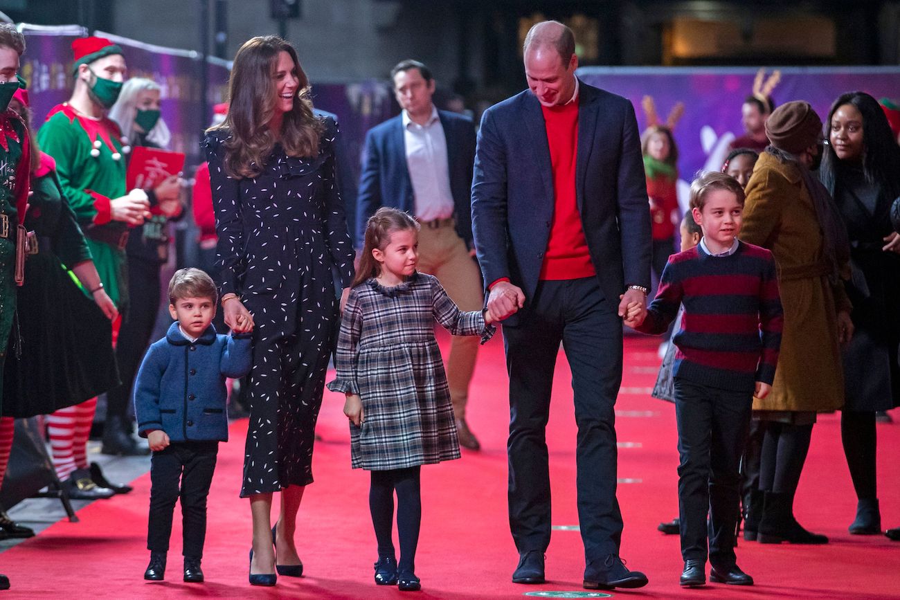 Kate Middleton and Prince William walking on a red carpet with their three kids