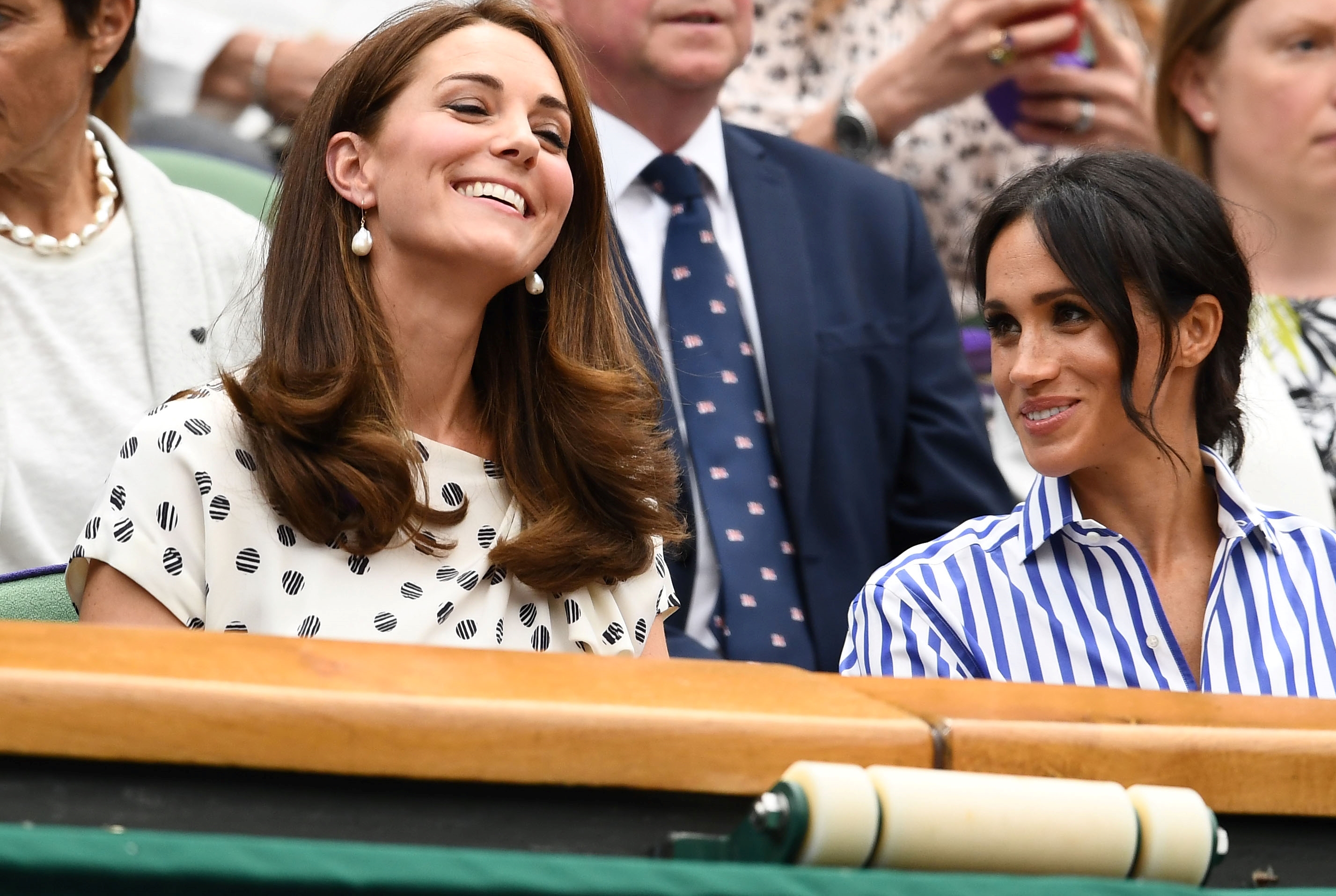 Kate Middleton and Meghan Markle smiling and laughing at the Wimbledon Tennis Championships in 2018 