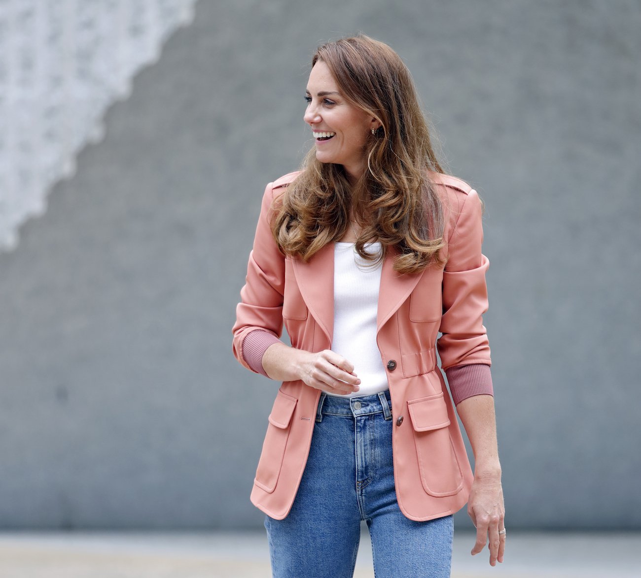 Kate Middleton wearing a salmon-colored blazer and blue jeans