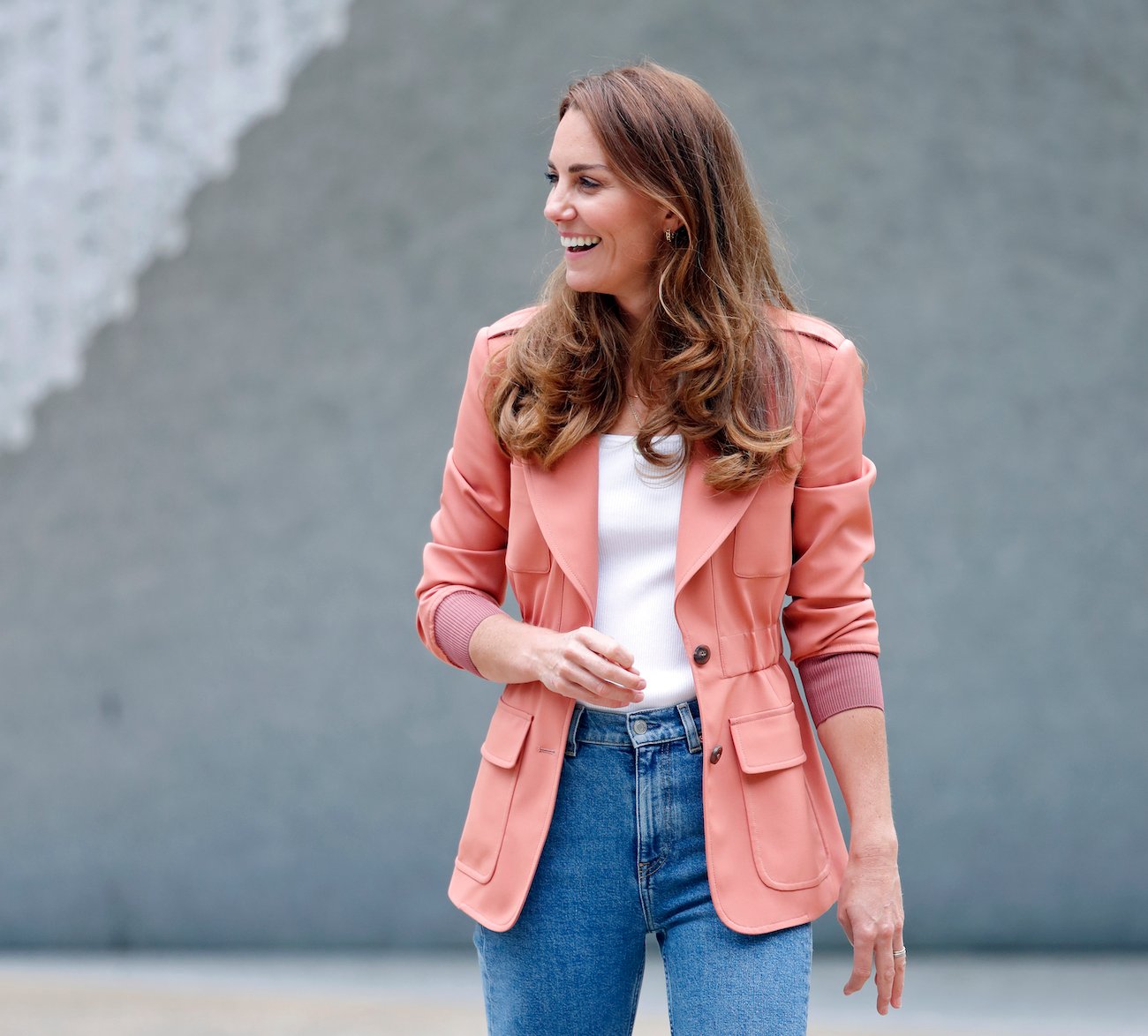 Kate Middleton wearing a salmon-colored blazer and blue jeans