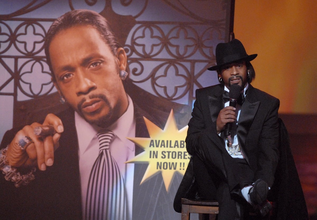 Katt Williams holding a microphone while wearing a suit.
