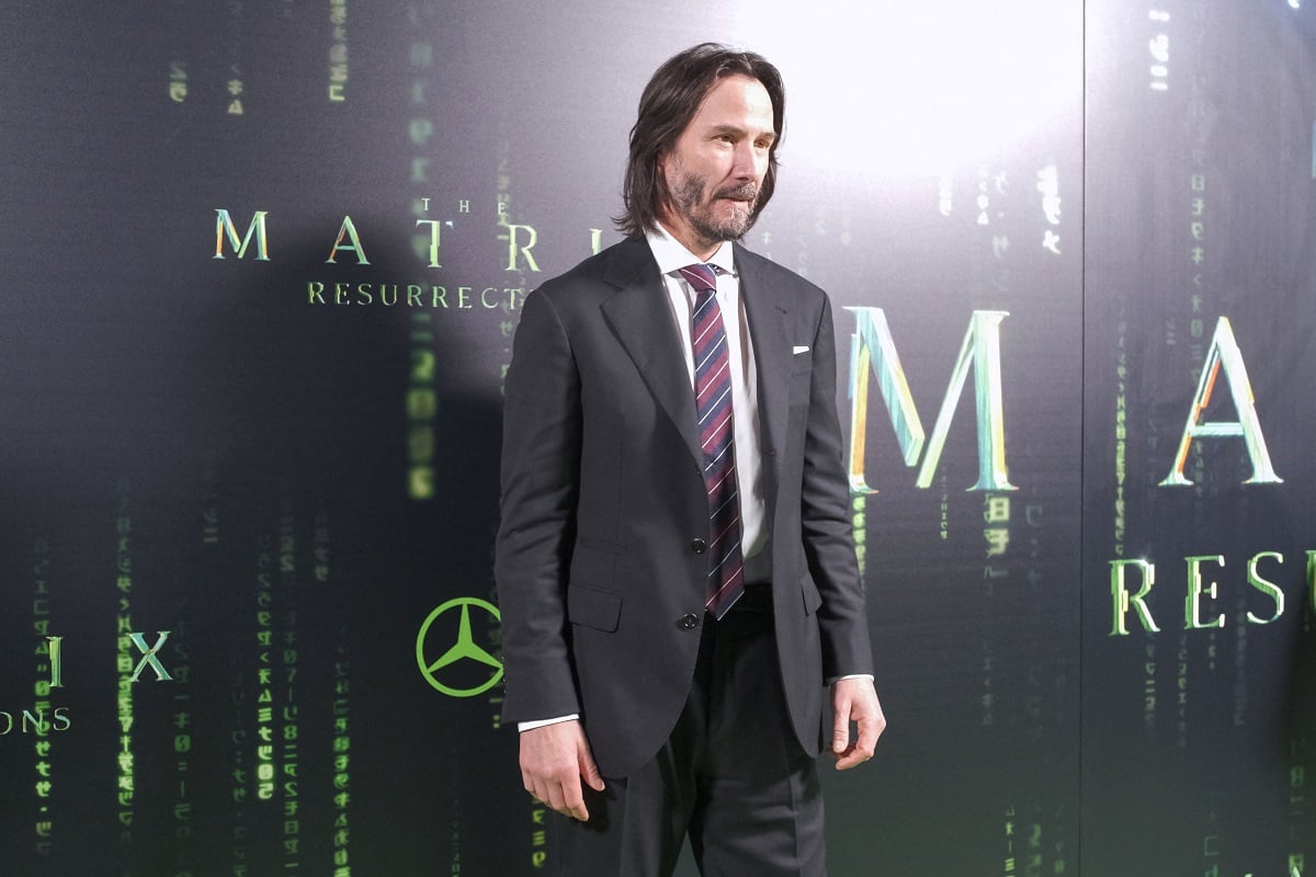 Keanu Reeves posing while wearing a suit.