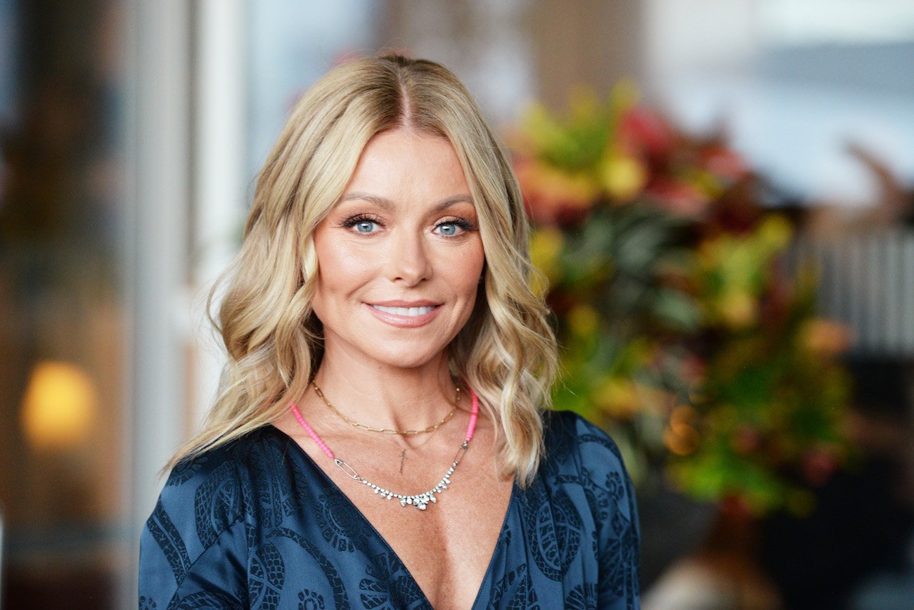 Kelly Ripa wearing a low-cut blue top and smiling into the camera