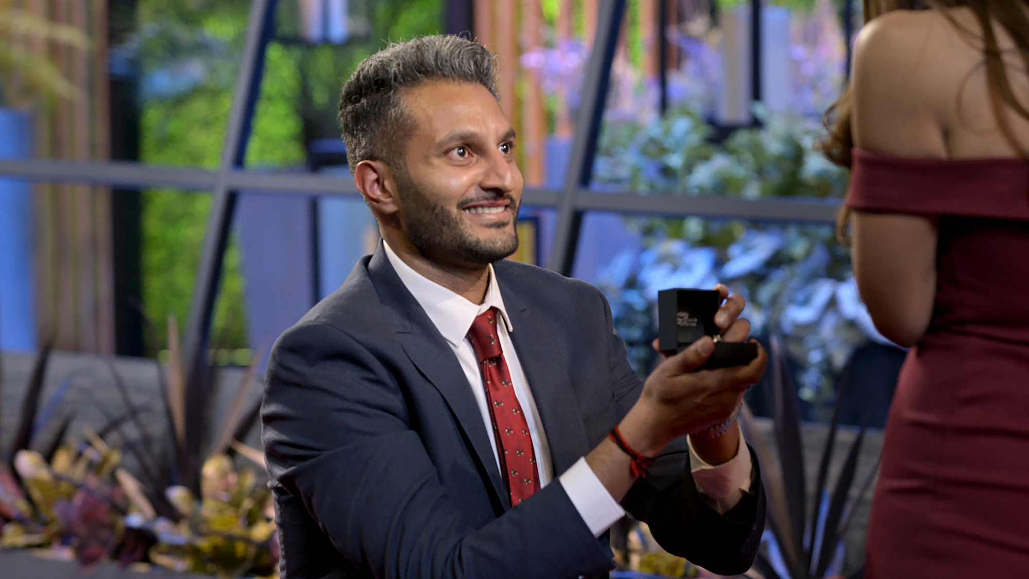 'Love is Blind' Season 2 star Shake Chatterjee wearing a suit and down on one knee while holding out an engagement ring.