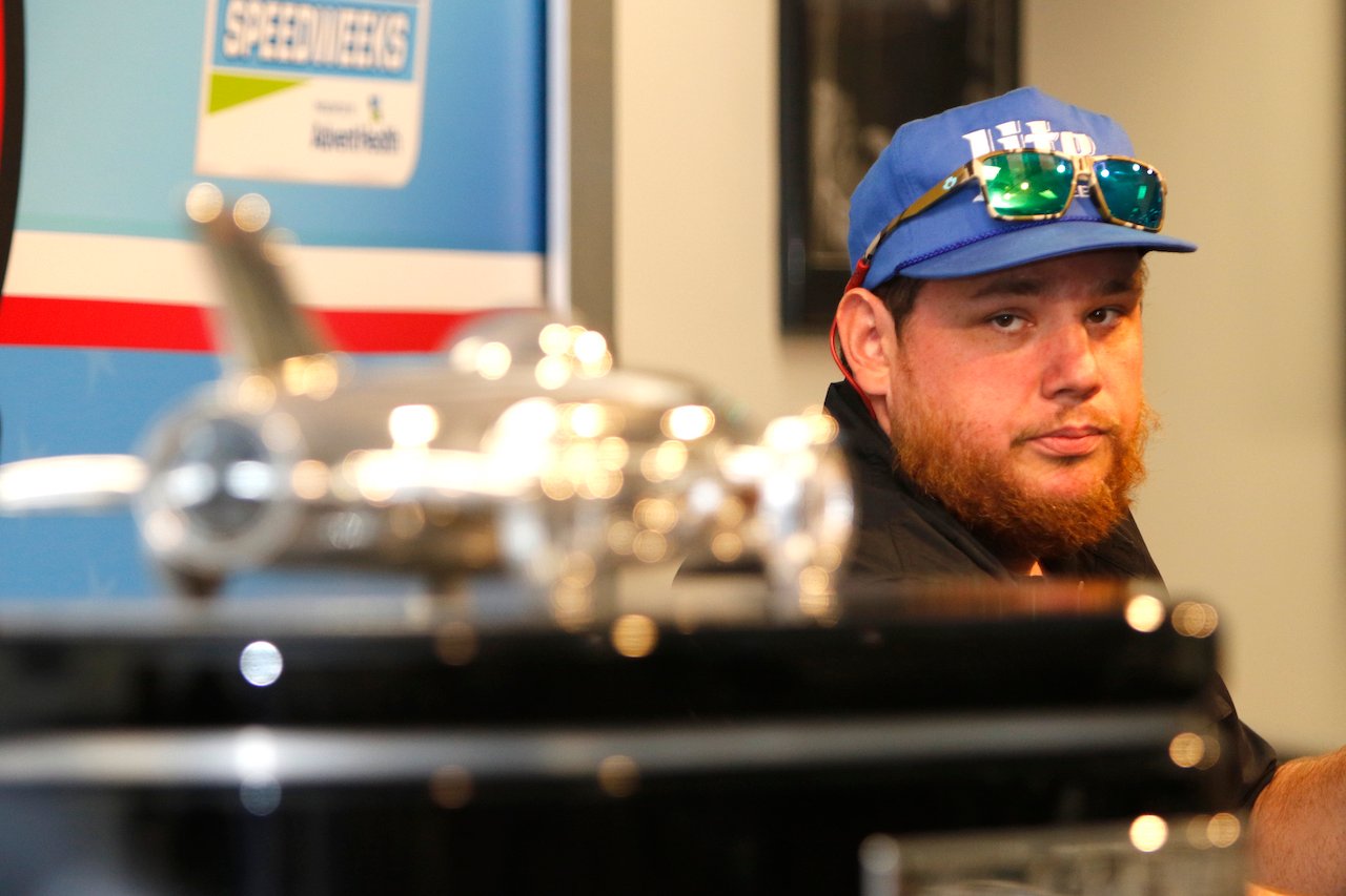 Luke Combs in a blue hat with sunglasses on top, poses with the Harley J Earl trophy at the NASCAR Cup Series Daytona 500