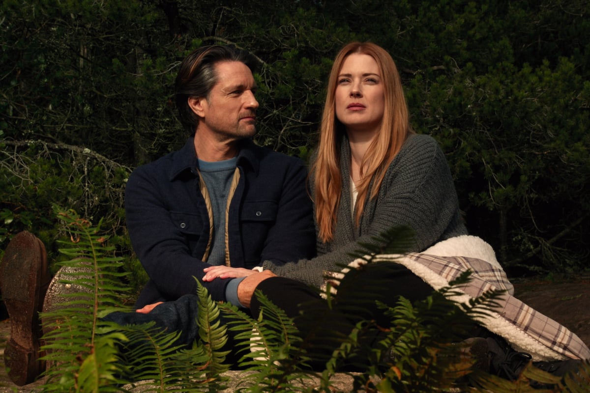 Martin Henderson as Jack Sheridan and Alexandra Breckenridge as Mel Monroe sitting on a tree stump in 'Virgin River'