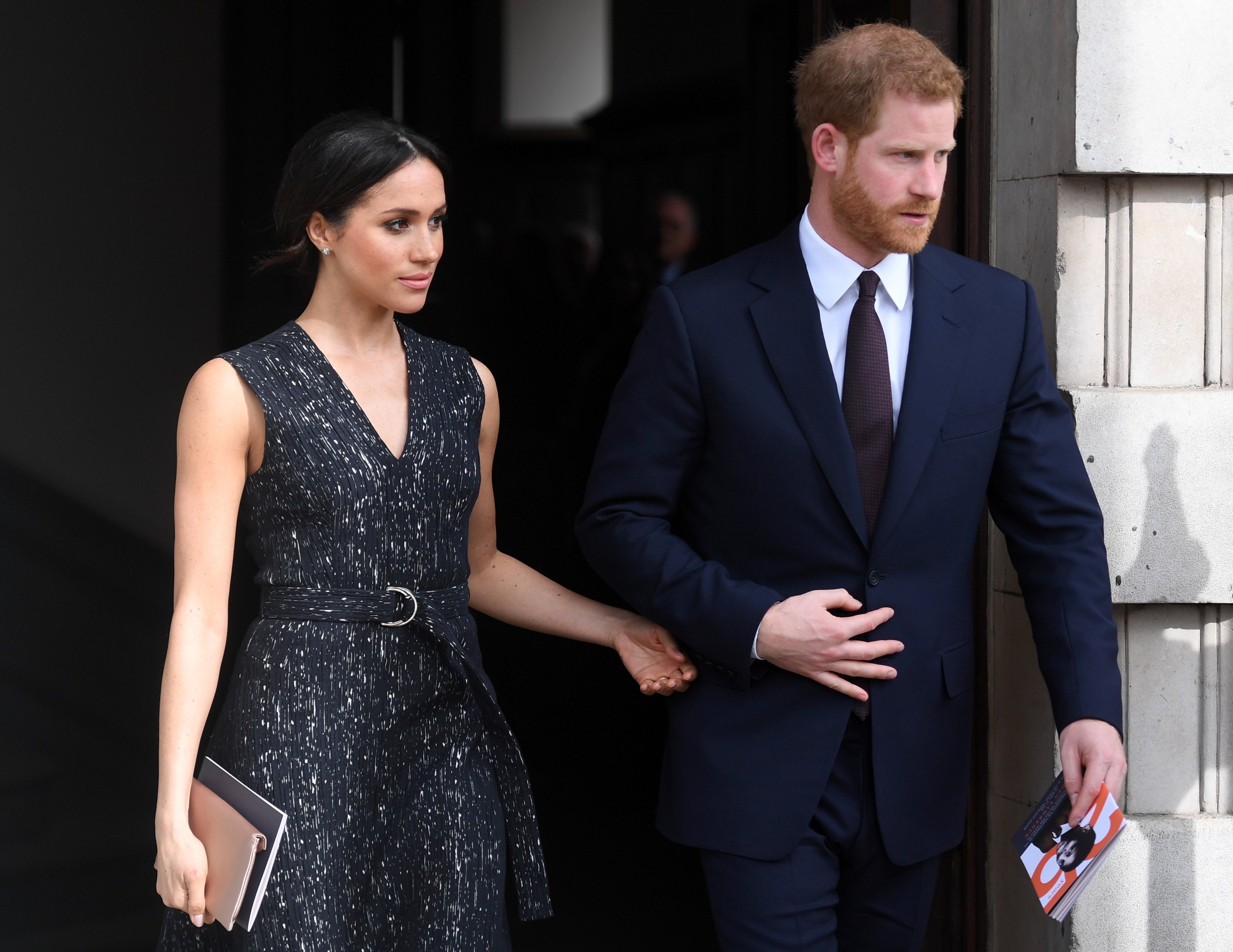 Meghan Markle making a subtle hand gesture toward Prince Harry as they exit a memorial service with months before their Oprah interview