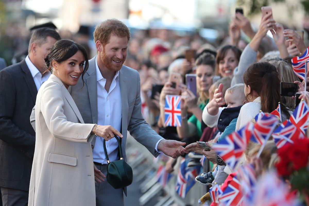Meghan Markle and Prince Harry hold hands greeting crowds