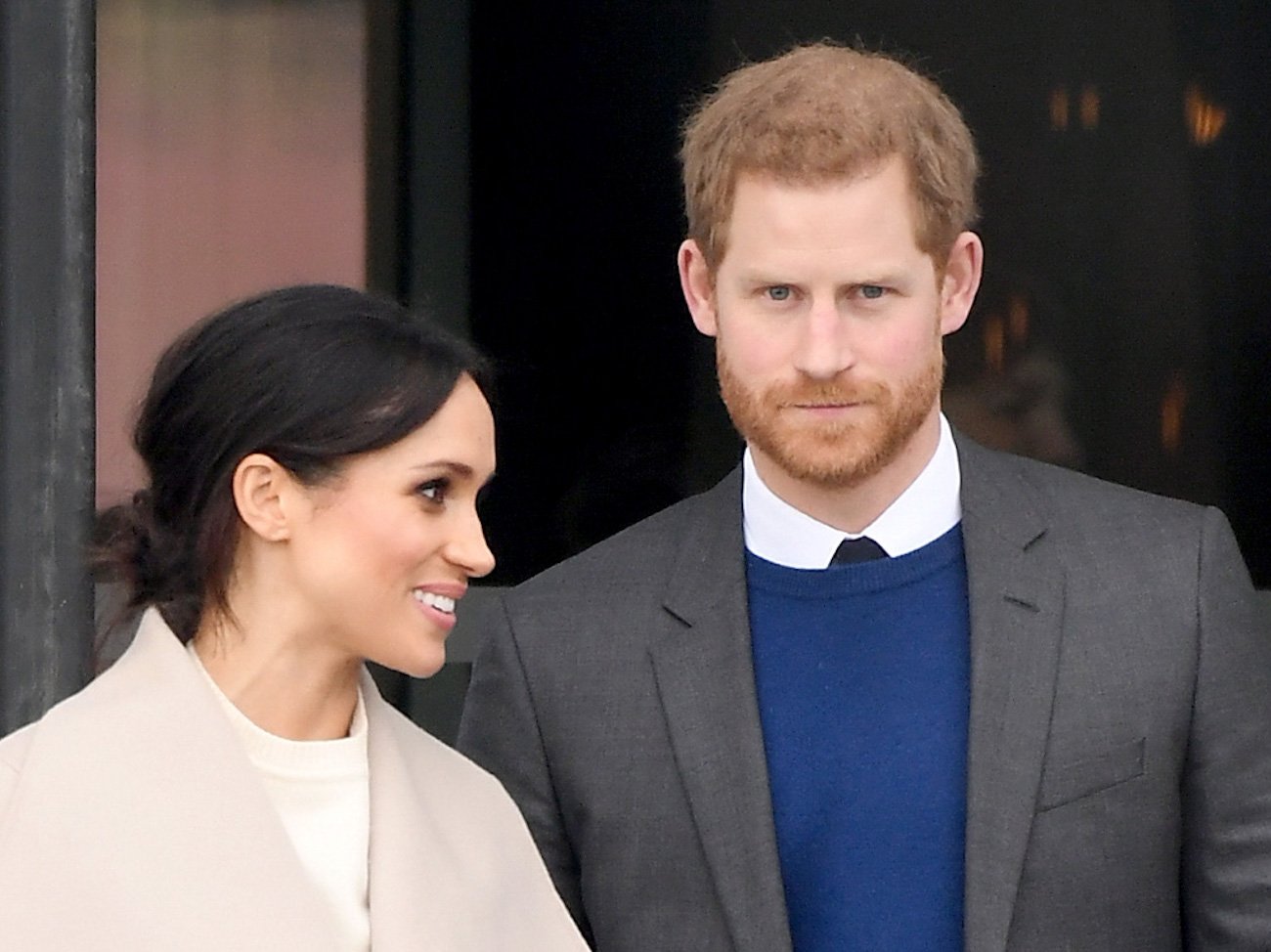 Meghan Markle smiling and looking to the right, Prince Harry looking on in the camera's direction