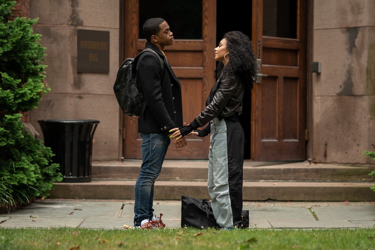Michael Rainey Jr as Tariq St. Patrick and Alix Lapri as Effie Morales wearing black shirts and jeans holding hands on a college campus in 'Power Book II: Ghost'