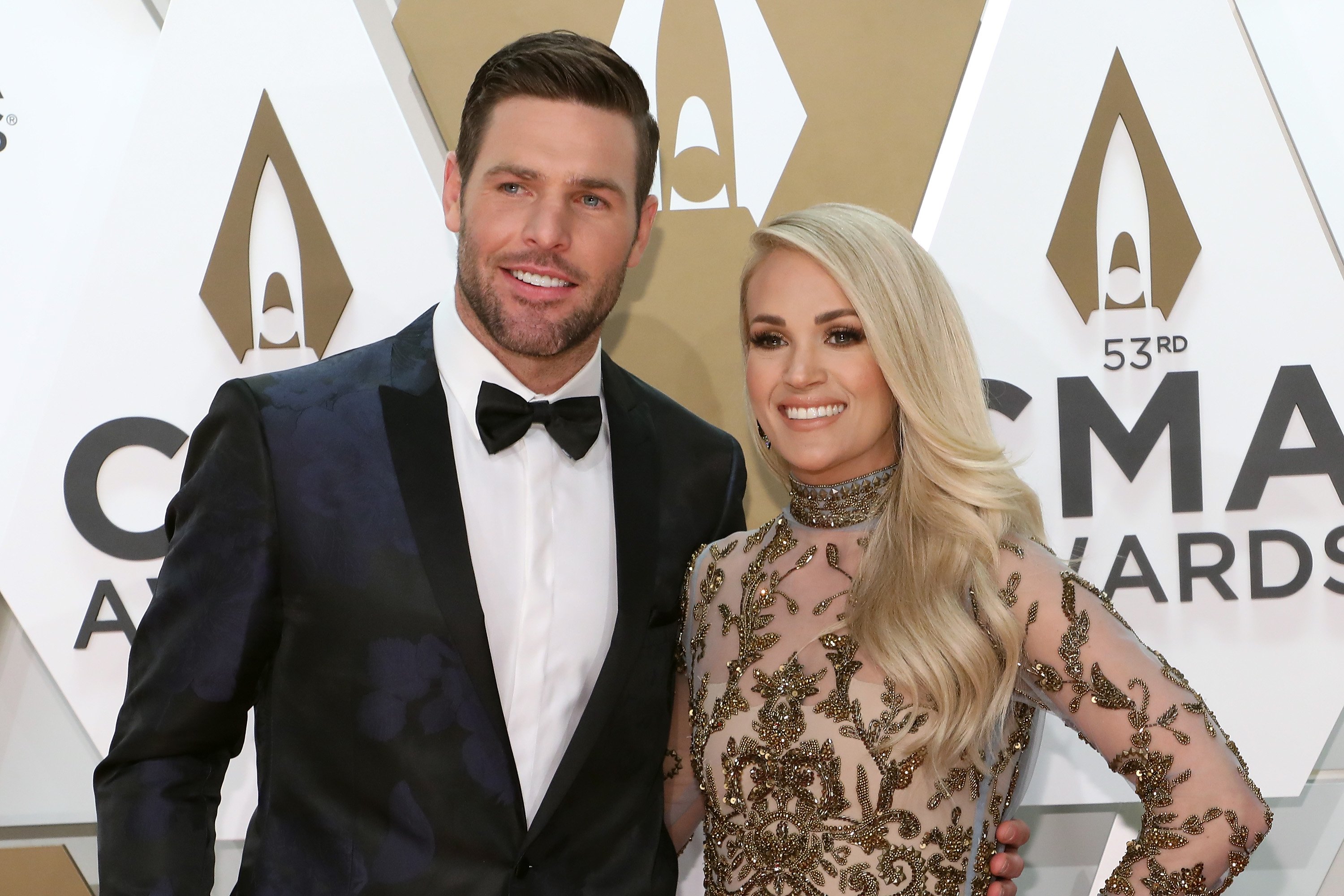 Mike Fisher and Carrie Underwood smiling on the carpet at the 53nd annual CMA Awards