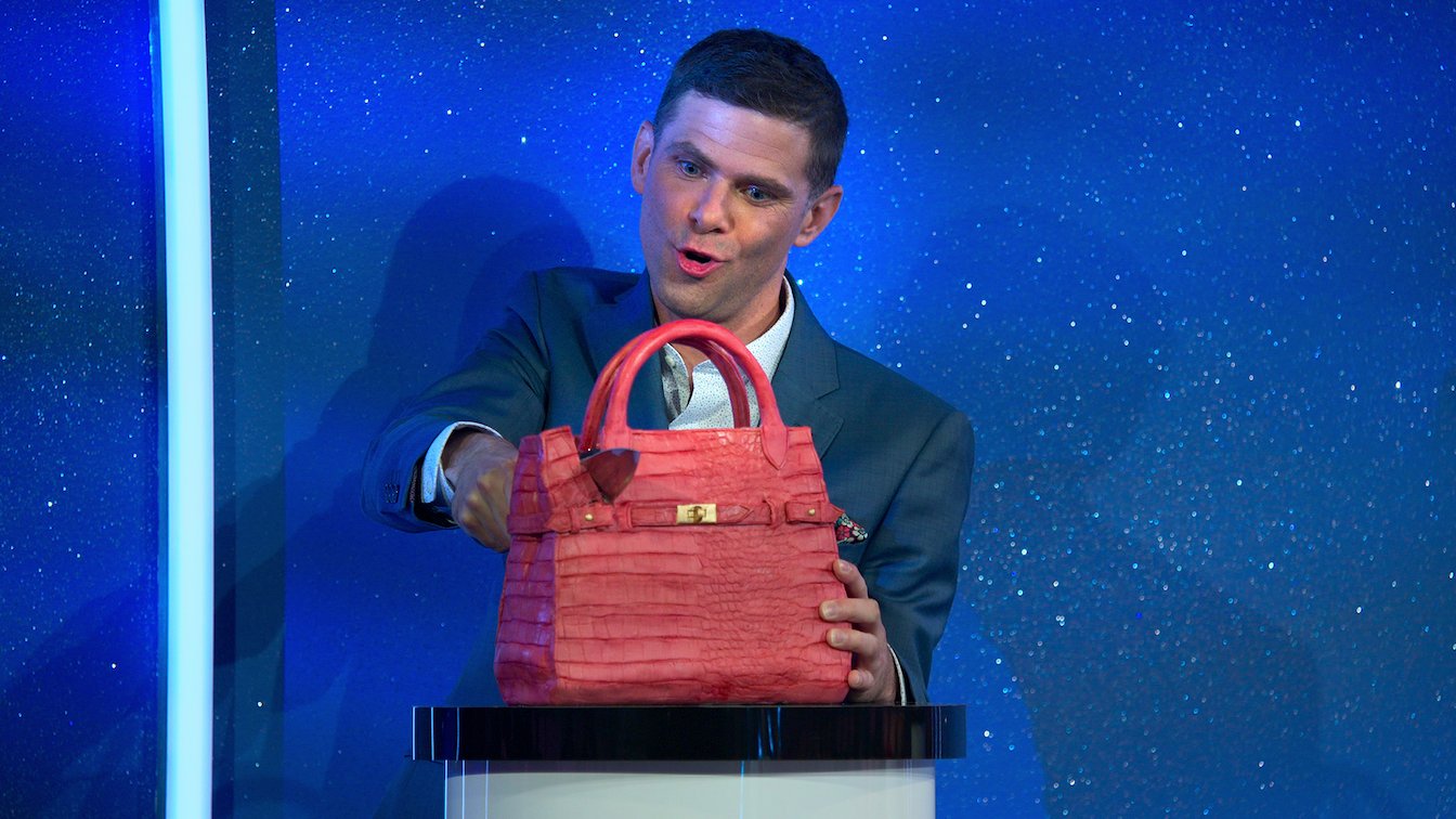 'Is it Cake?' host Mikey Day cutting into a cake that looks like a purse