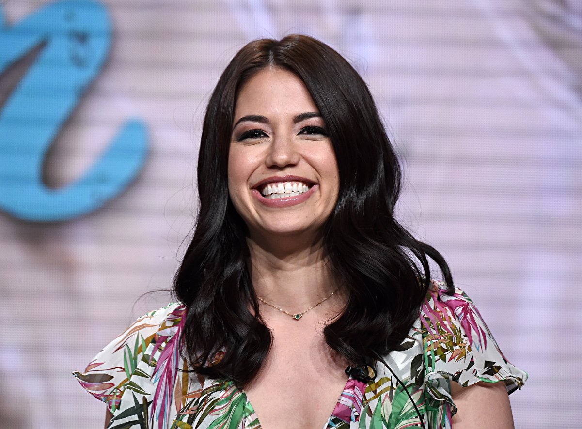 Food Network personality Molly Yeh wears a flutter-sleeved print blouse in this photograph.