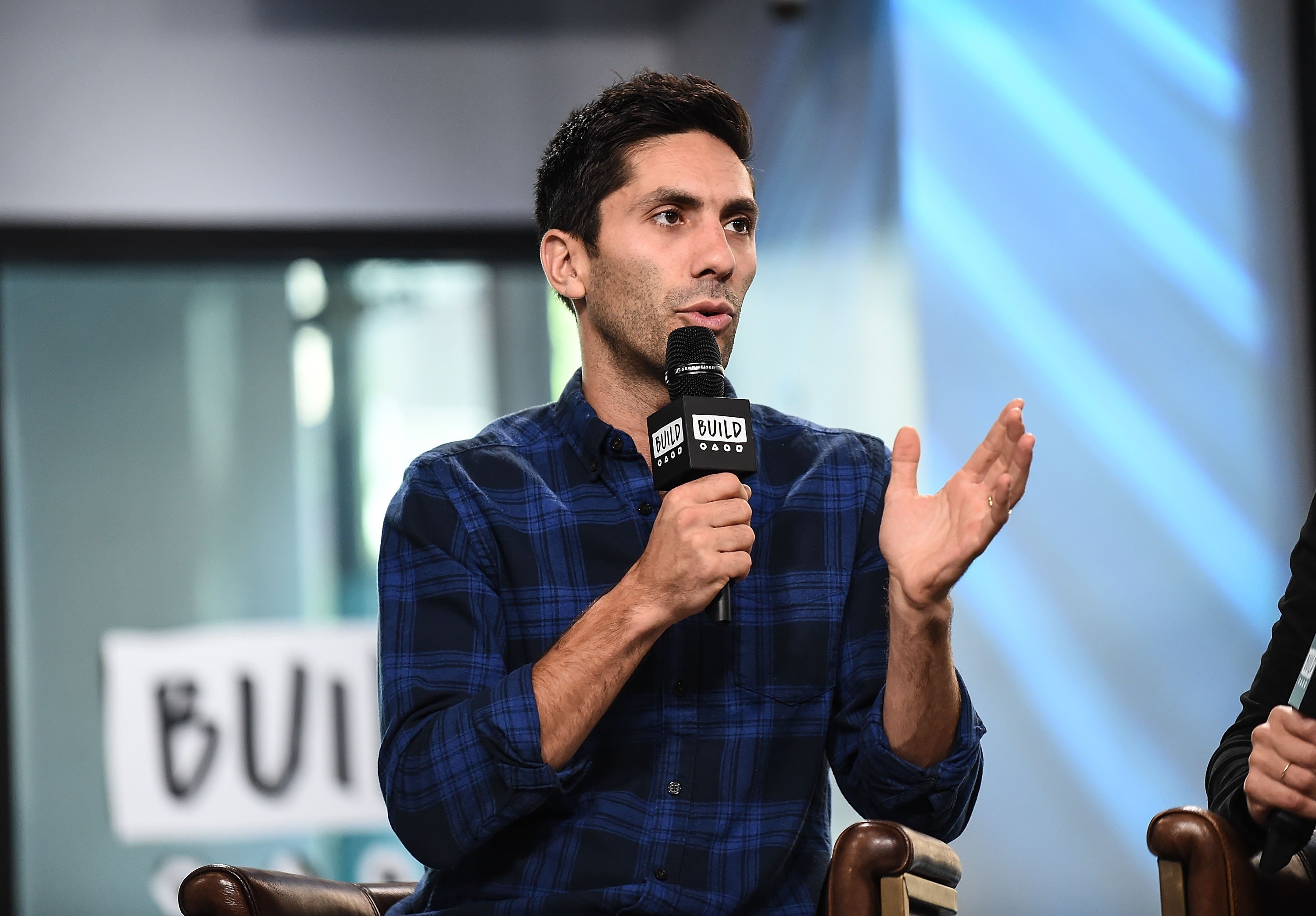 Nev Schulman holds a microphone while speaking on AOL's BUILD Series.