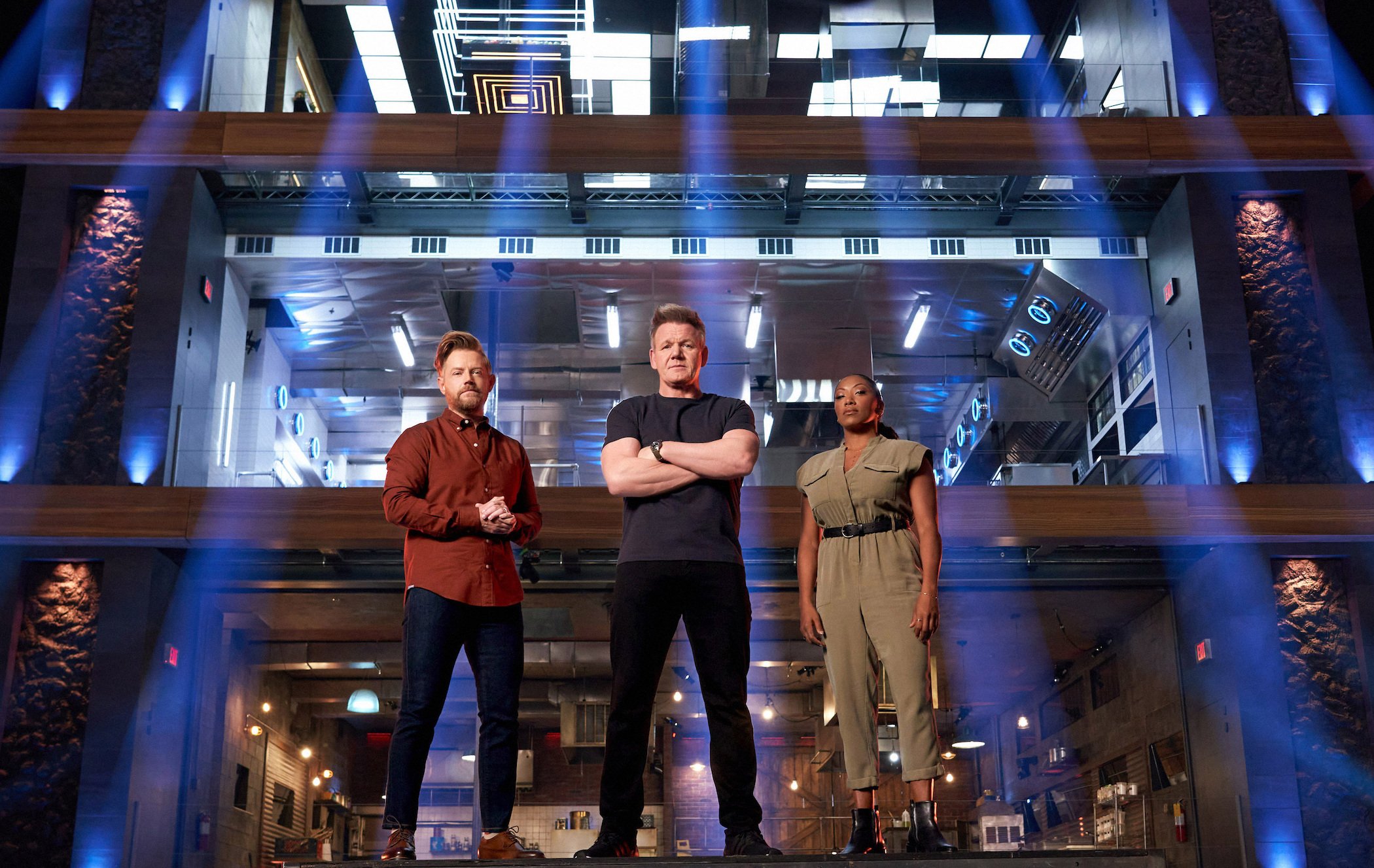 Richard Blais, Gordon Ramsay, and Nyesha Arrington standing together in front of the 'Next Level Chef' three-tiered kitchen