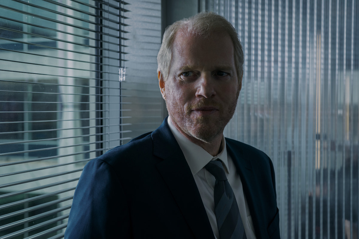 Noah Emmerich wears a suit and looks on in a scene from 'Suspicion' Season 1 Episode 6 'Be the Gray Man'