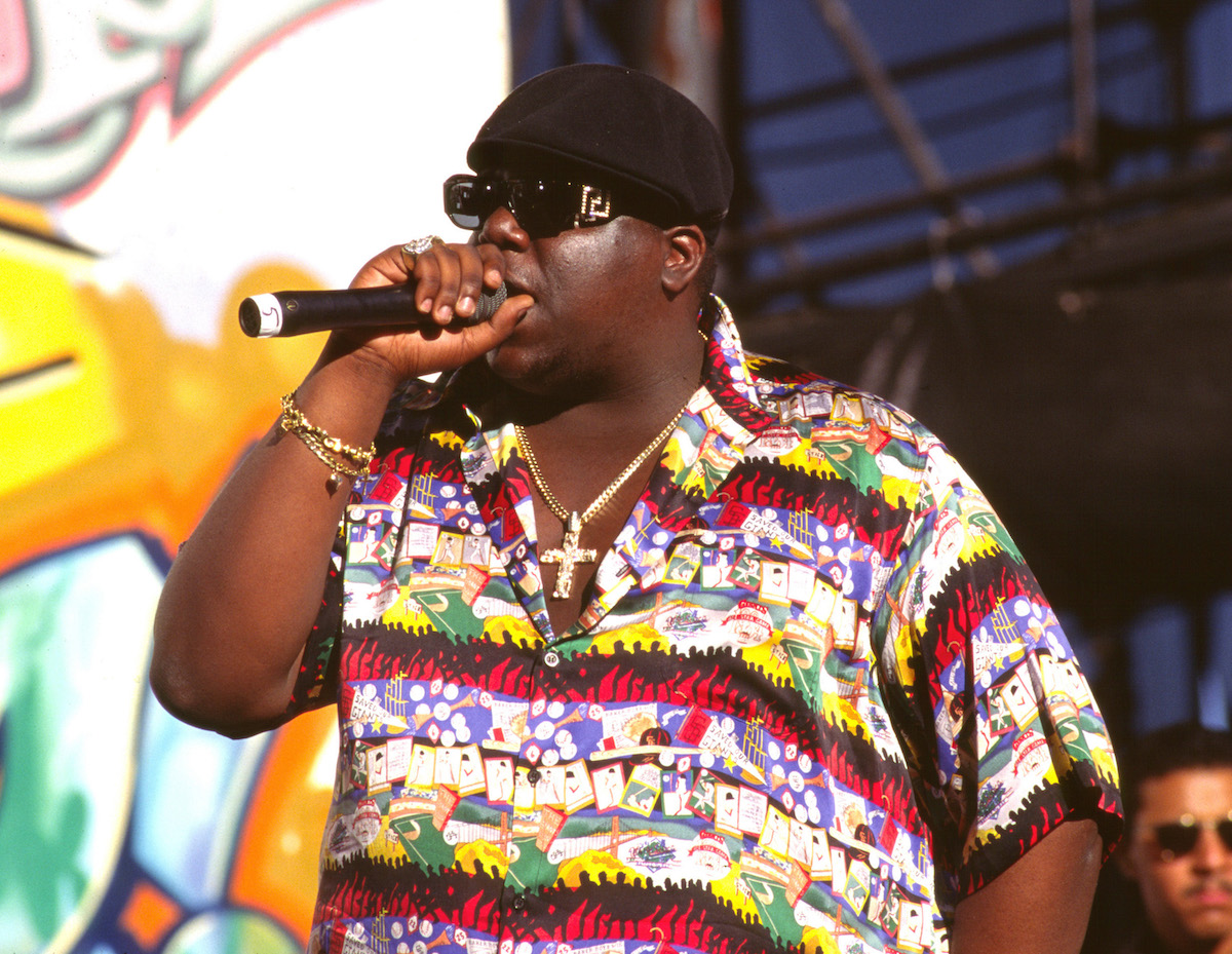 Rapper The Notorious B.I.G. stands on stage in a colorful shirt while performing in 1995