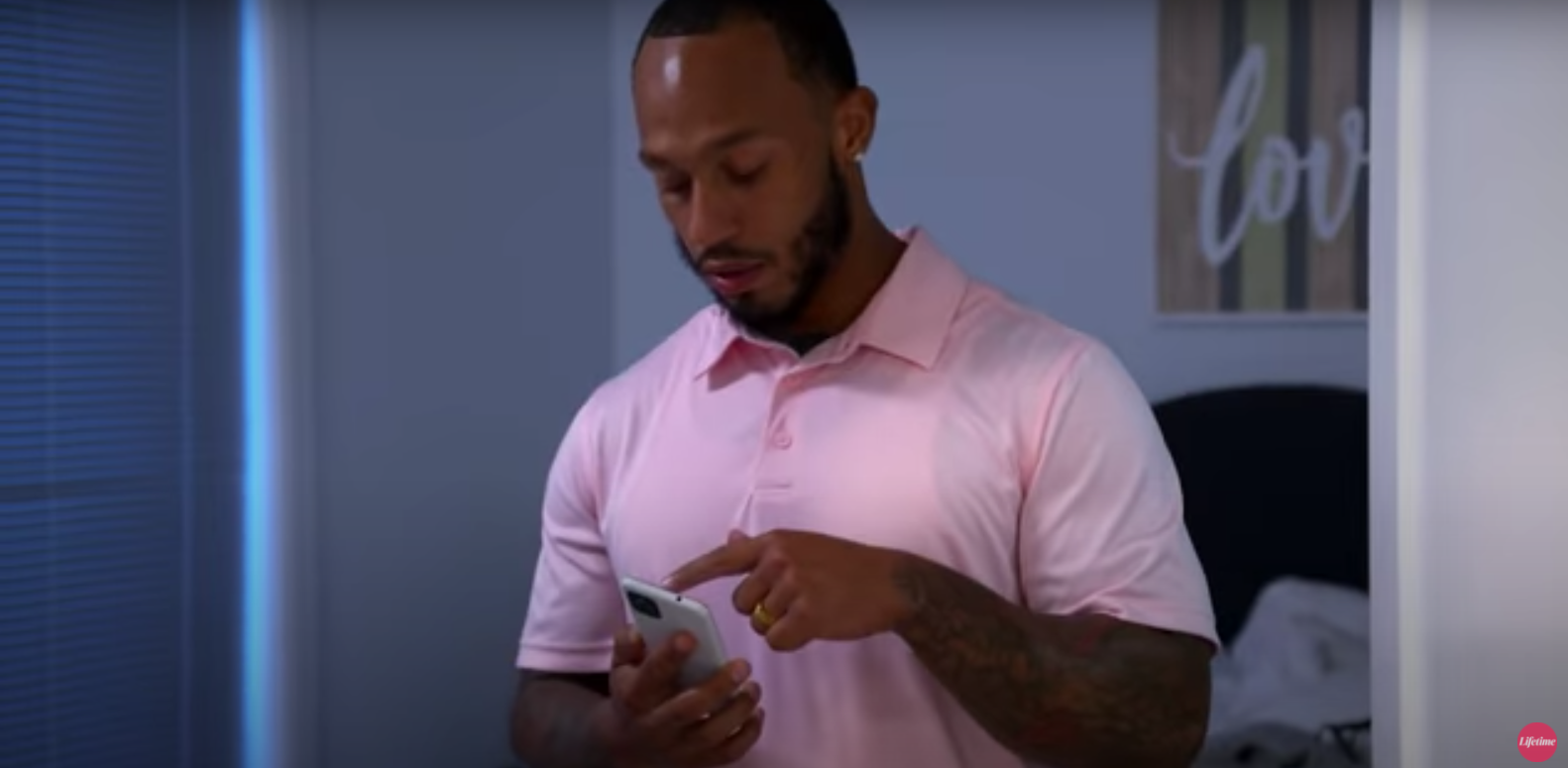 Olajuwon holding a phone and wearing a pink polo in 'Married at First Sight'