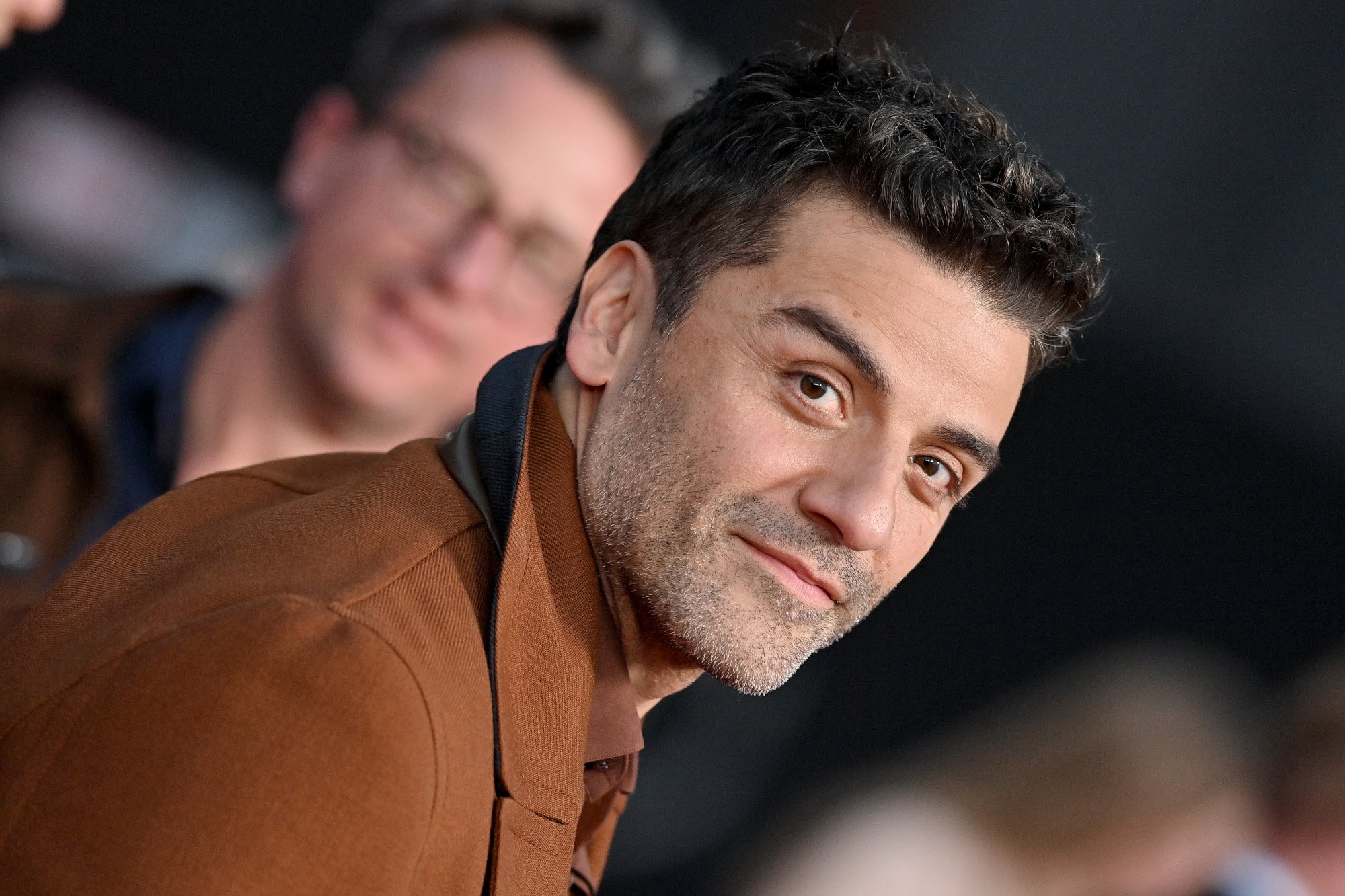 Oscar Isaac at the premiere for Marvel's 'Moon Knight.' He's wearing a light brown jacket and smiling.