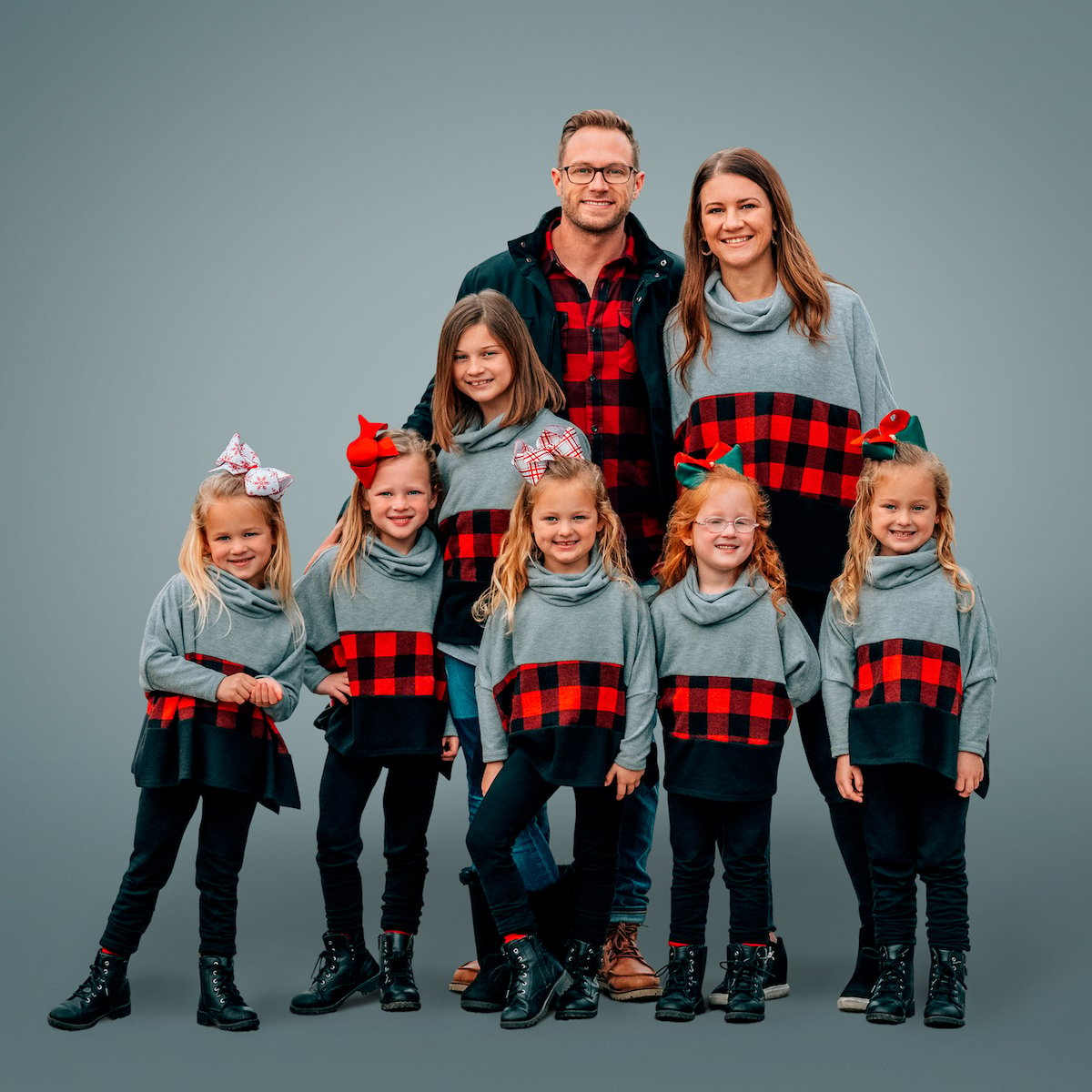 photo of the Busby family from 'OutDaughtered', wearing matching gray and plaid tops, on gray background
