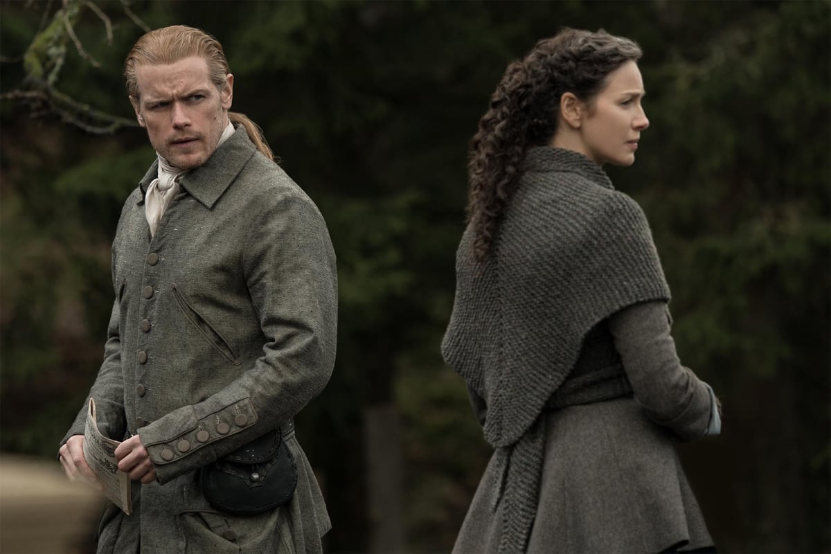 Outlander stars Sam Heughan as Jamie Fraser and Caitriona Balfe as Claire Fraser in character and looking away from each other.