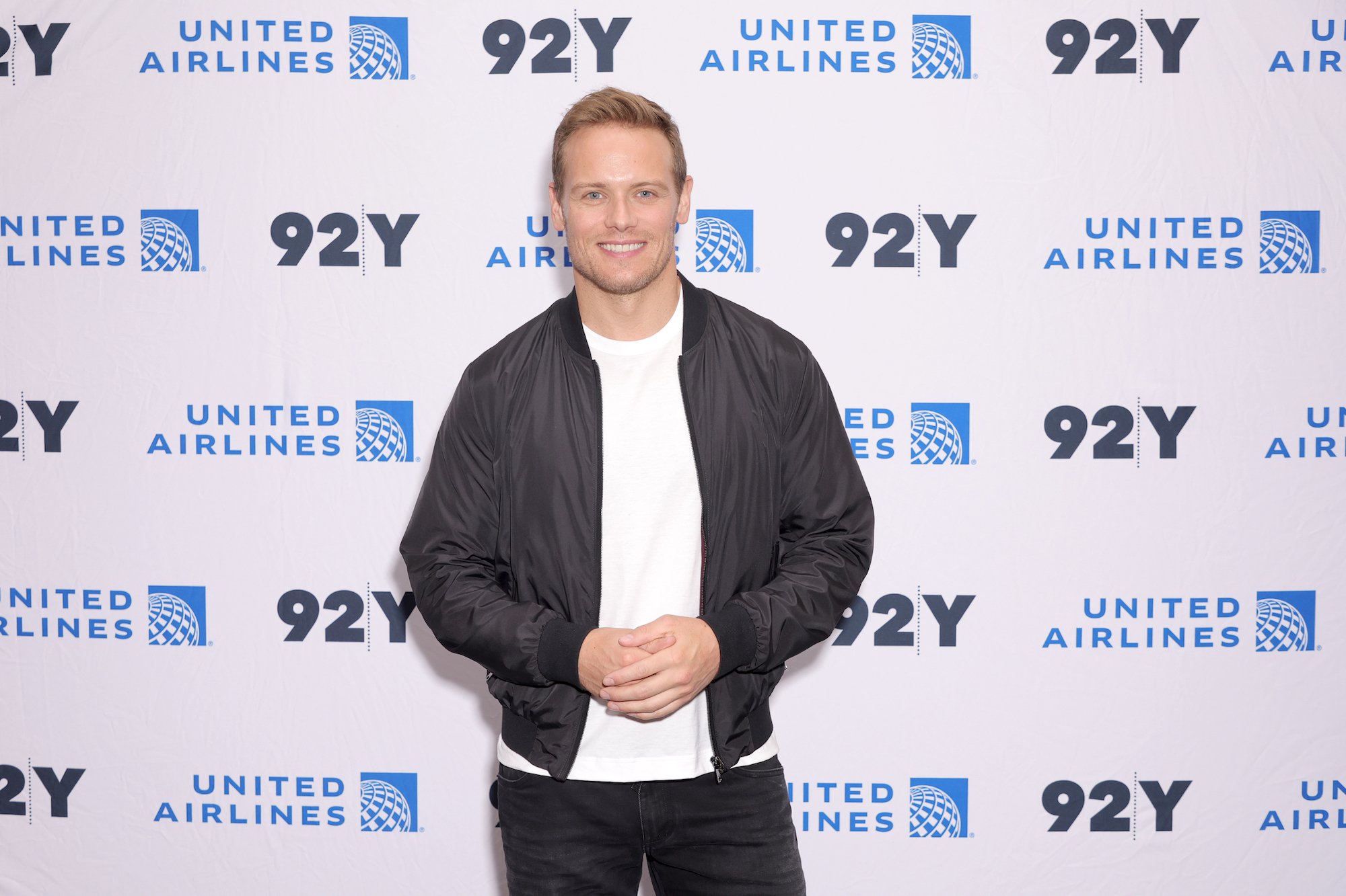 'Outlander' star Sam Heughan smiles and folds his hands