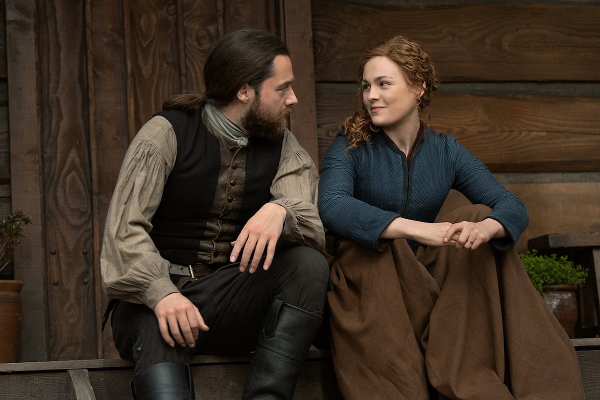 'Outlander' stars Richard Rankin and Sophie Skelton sit on a porch