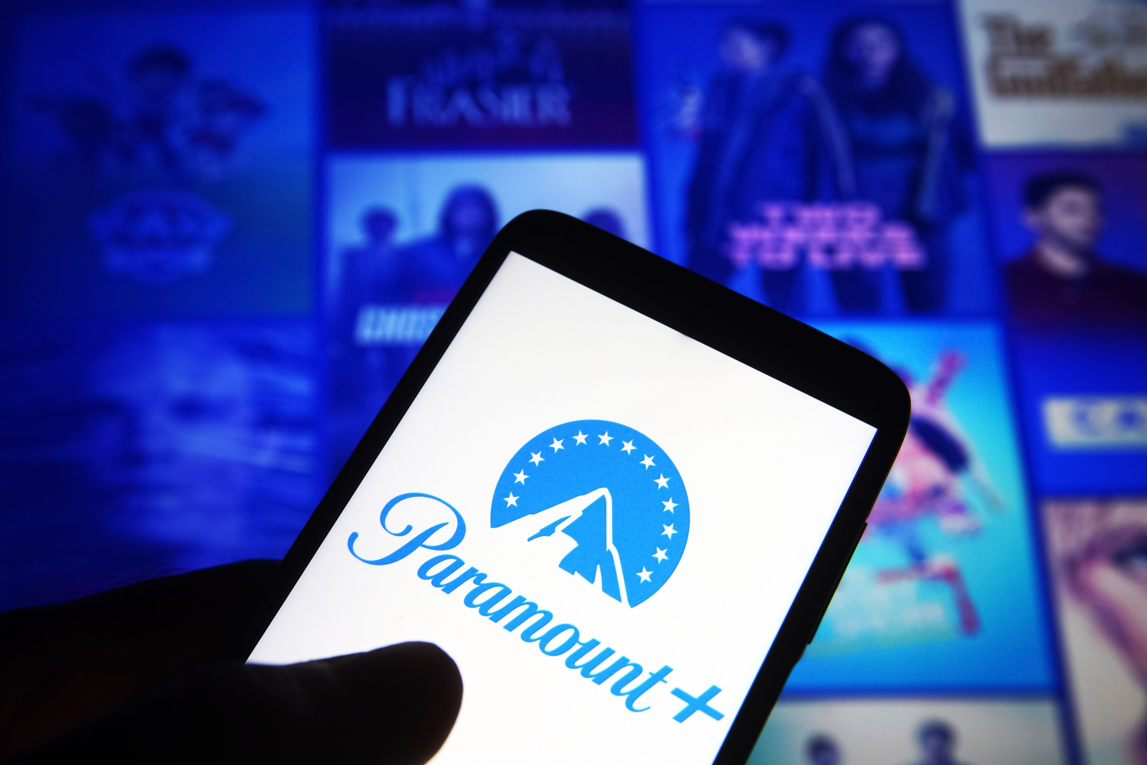 Paramount+ logo is seen on a smartphone against its website in the background