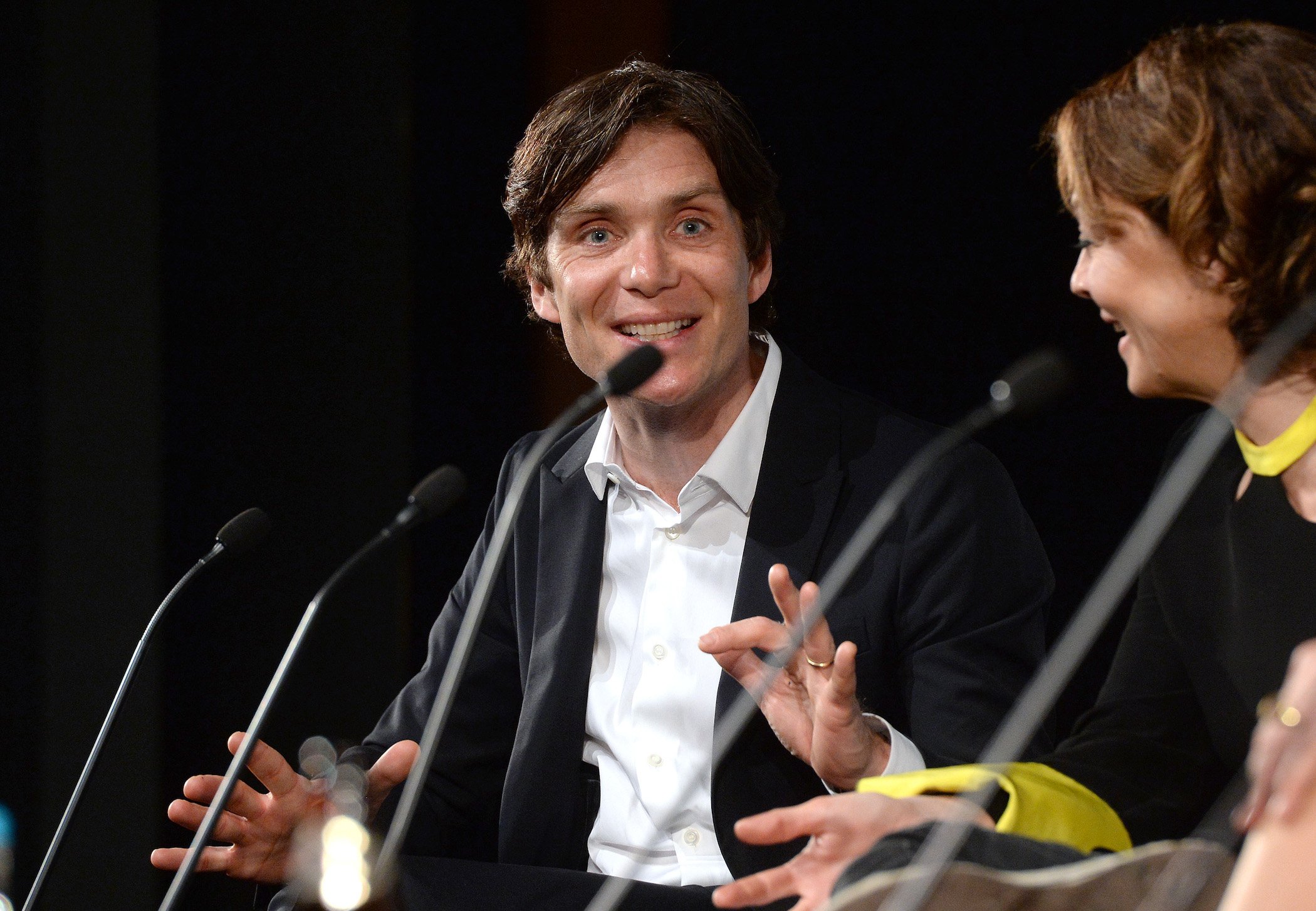Cillian Murphy during a Q&A for 'Peaky Blinders' Season 6. He's against a black background in front of a microphone.