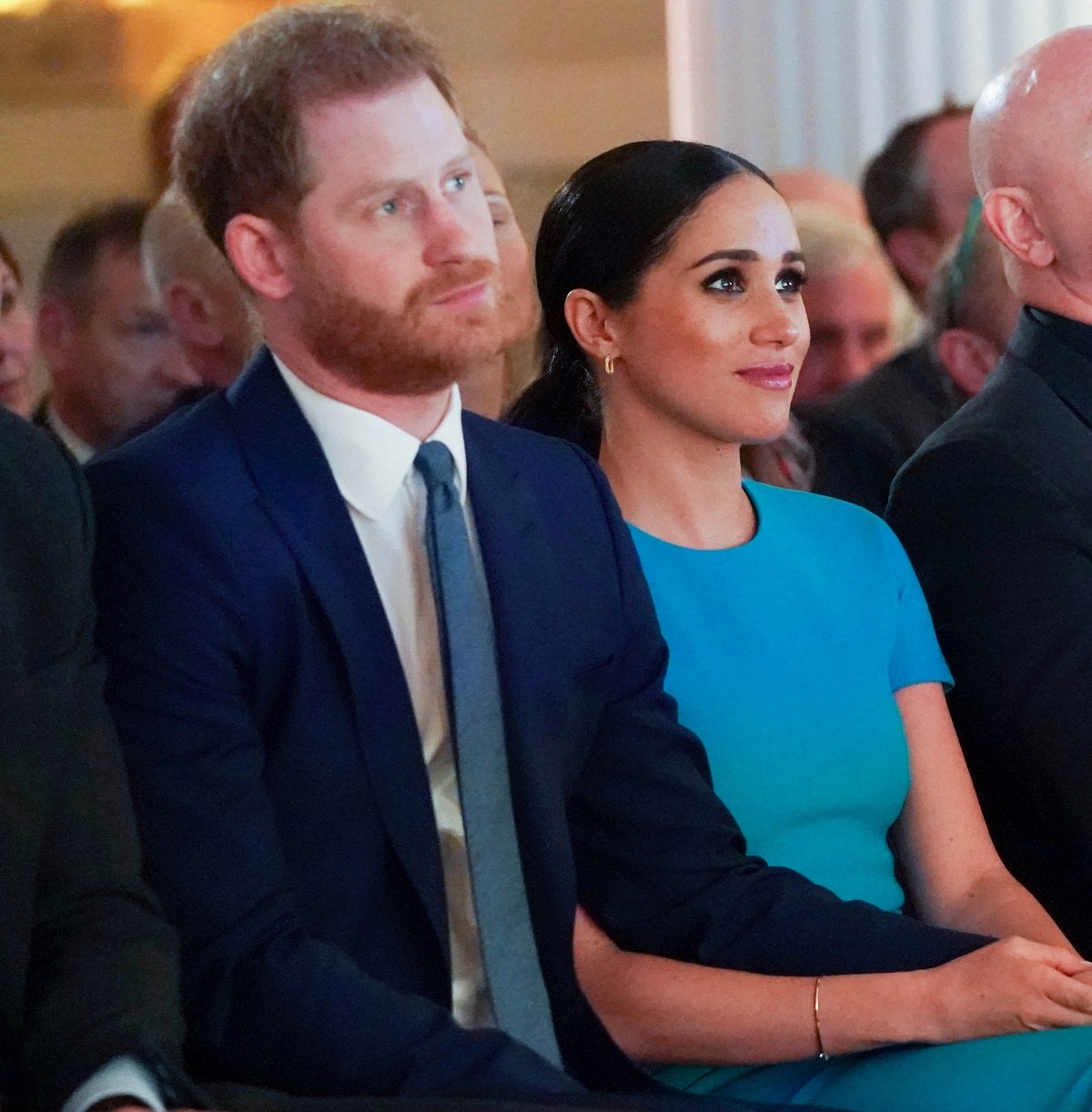 Prince Harry and Meghan Markle sitting next to eachother and holding hands at the annual Endeavour Fund Awards