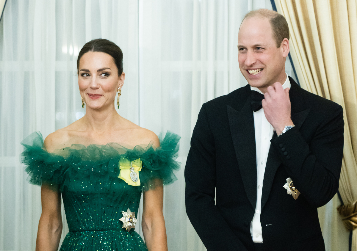 Kate Middleton and Prince William standing next to each other in formal attire — the Duchess of Cambridge in a green dress and the Duke of Cambridge in a black suit