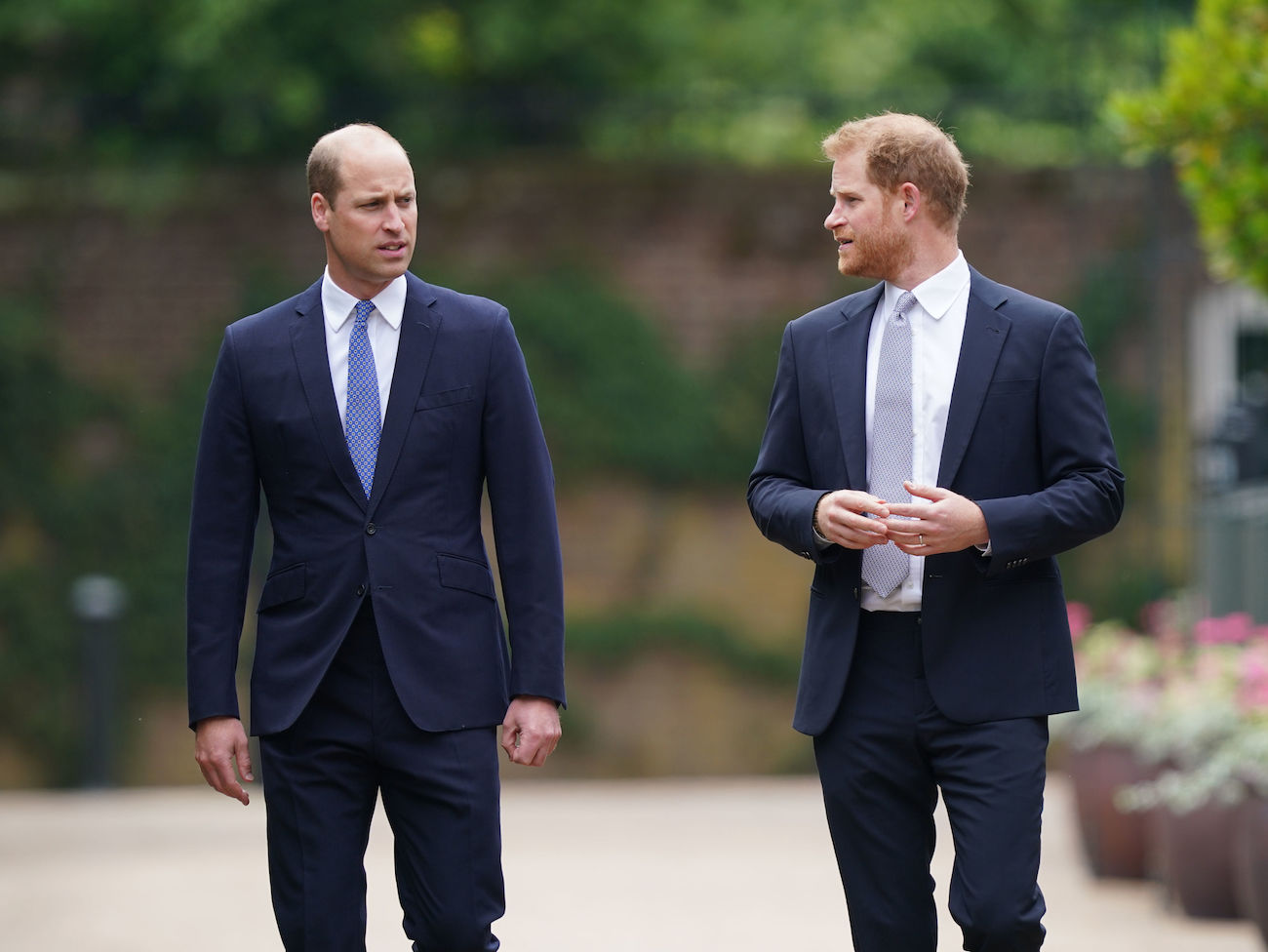 Prince William and Prince Harry wearing suits and walking next to each other