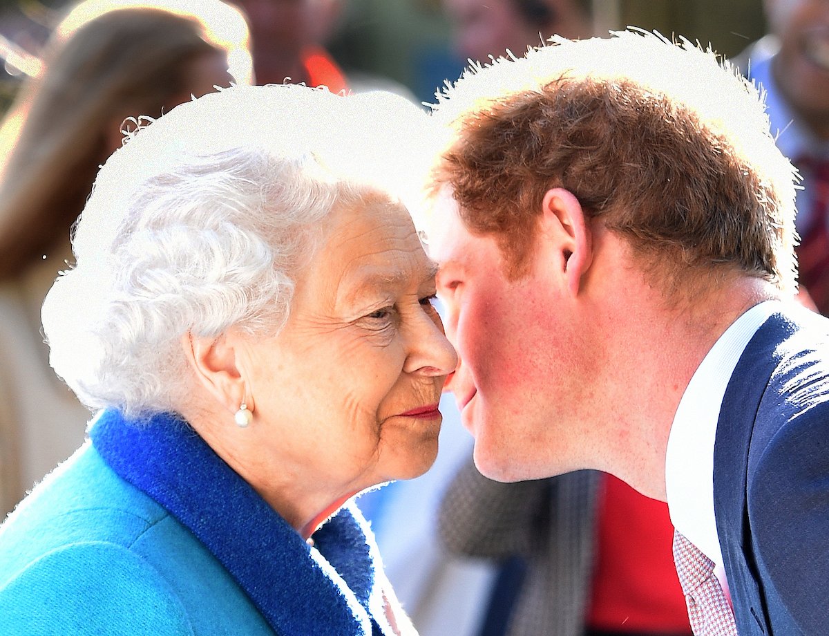 Queen Elizabeth II and Prince Harry lean in to kiss each other on the cheek