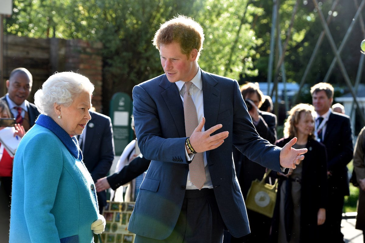 Queen Elizabeth II wears blue standing next to Prince Harry
